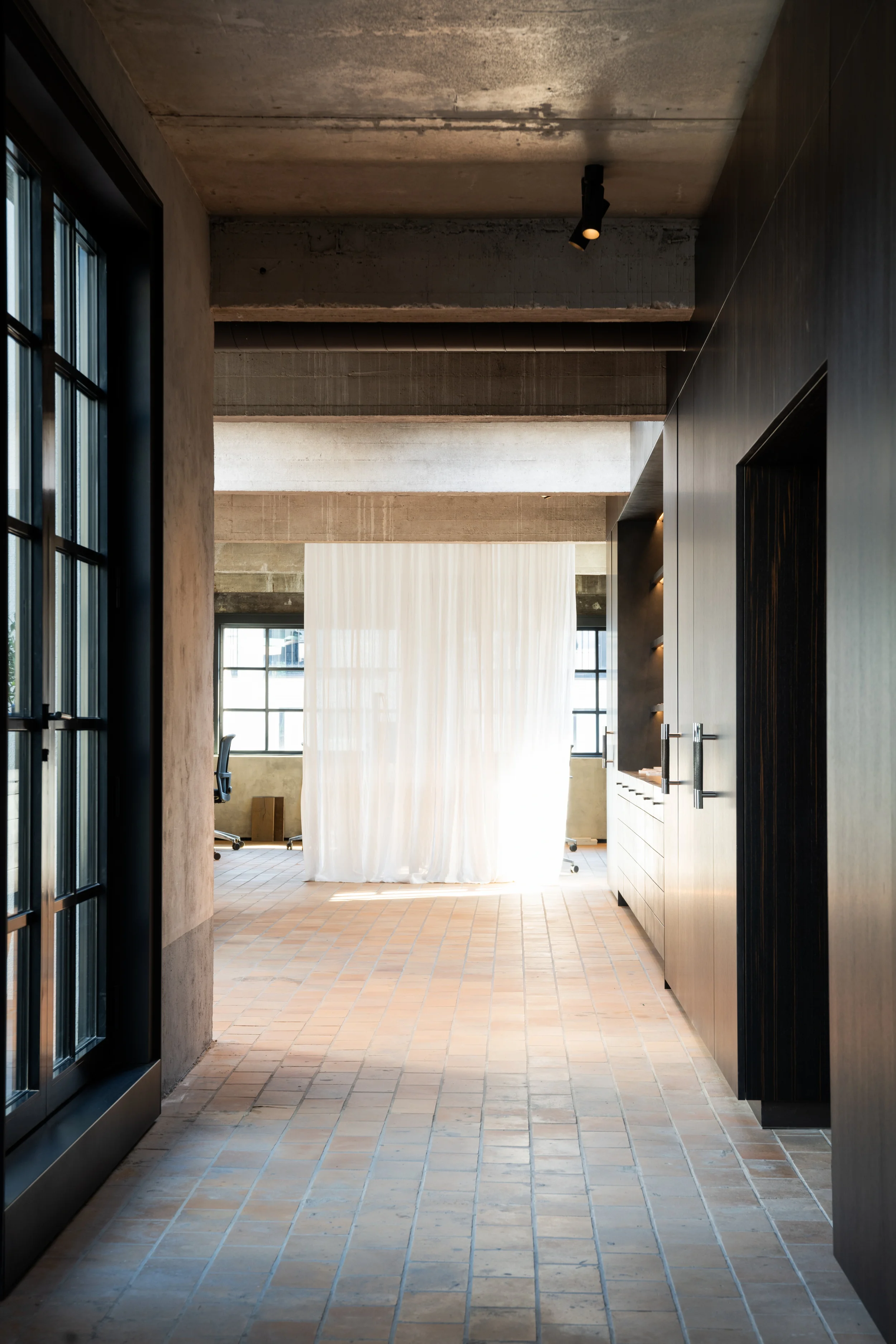 Black Kreon Holon 60 Directional Surface spotlight in a corridor with terracotta floor and dark wood panels