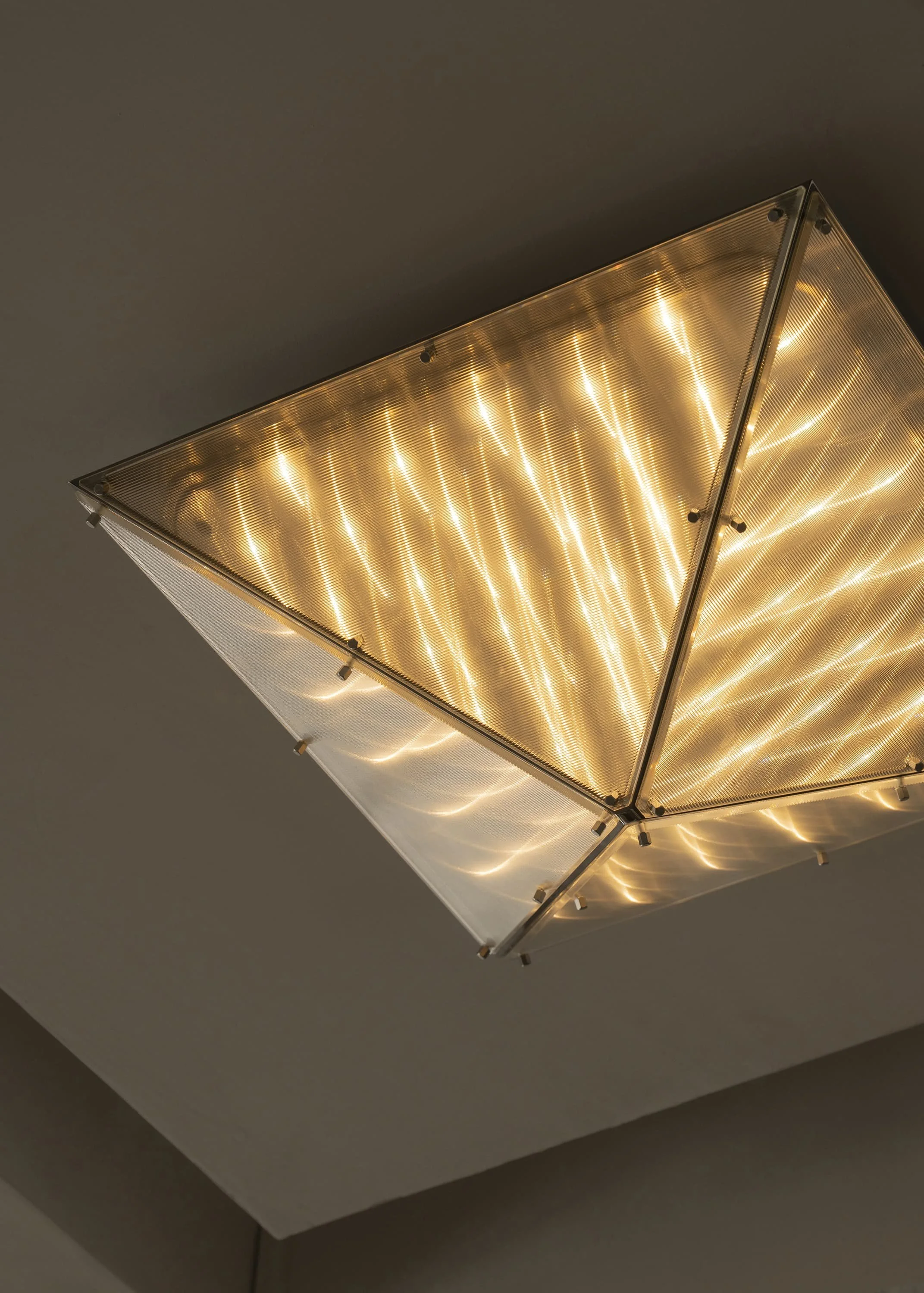 Geometric ceiling fixture emitting warm atmospheric light, Fragment 06.