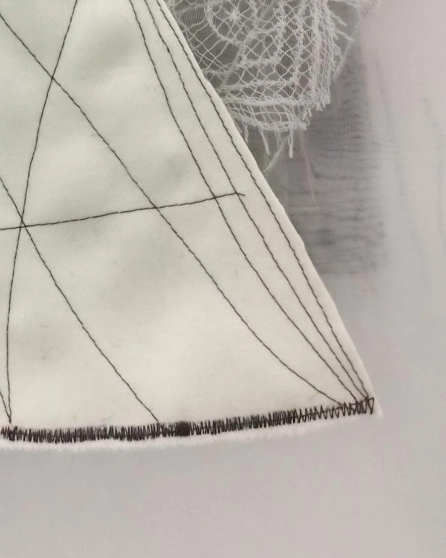 Handcrafted textile wall art featuring geometric stitching and delicate fabric layering showcased in a Barcelona contemporary art gallery