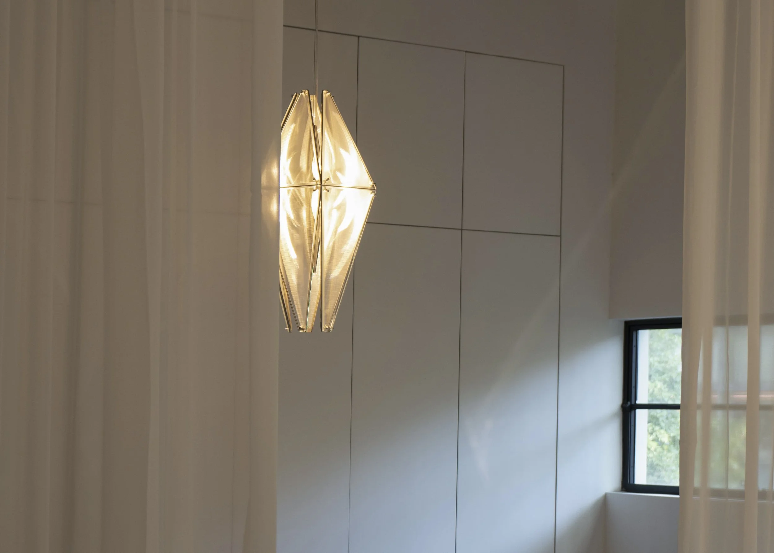 Modern ceiling pendant with sculptural geometric form and soft interior glow.