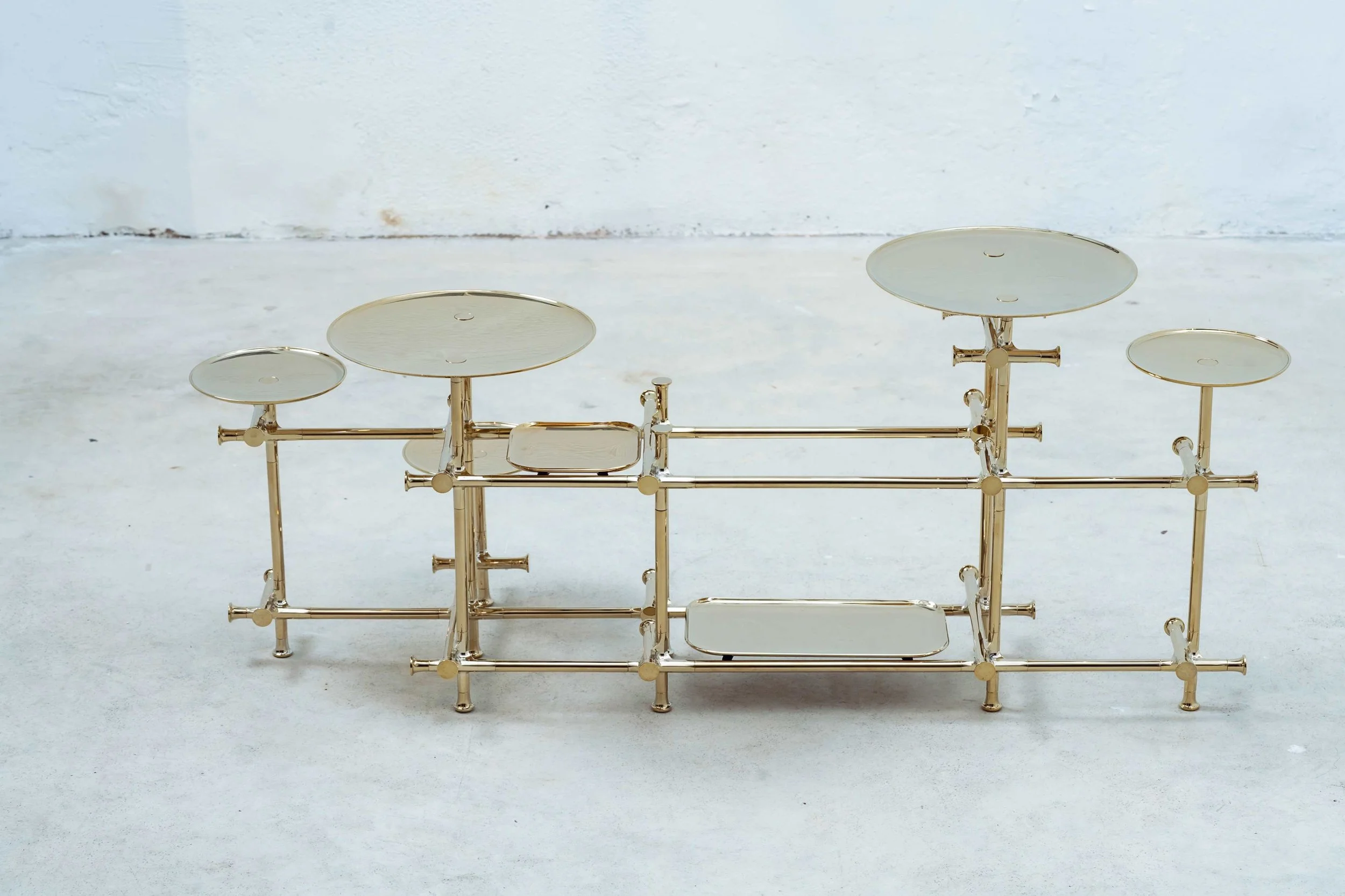 Modern sculptural console with elevated metal trays arranged in geometric composition.