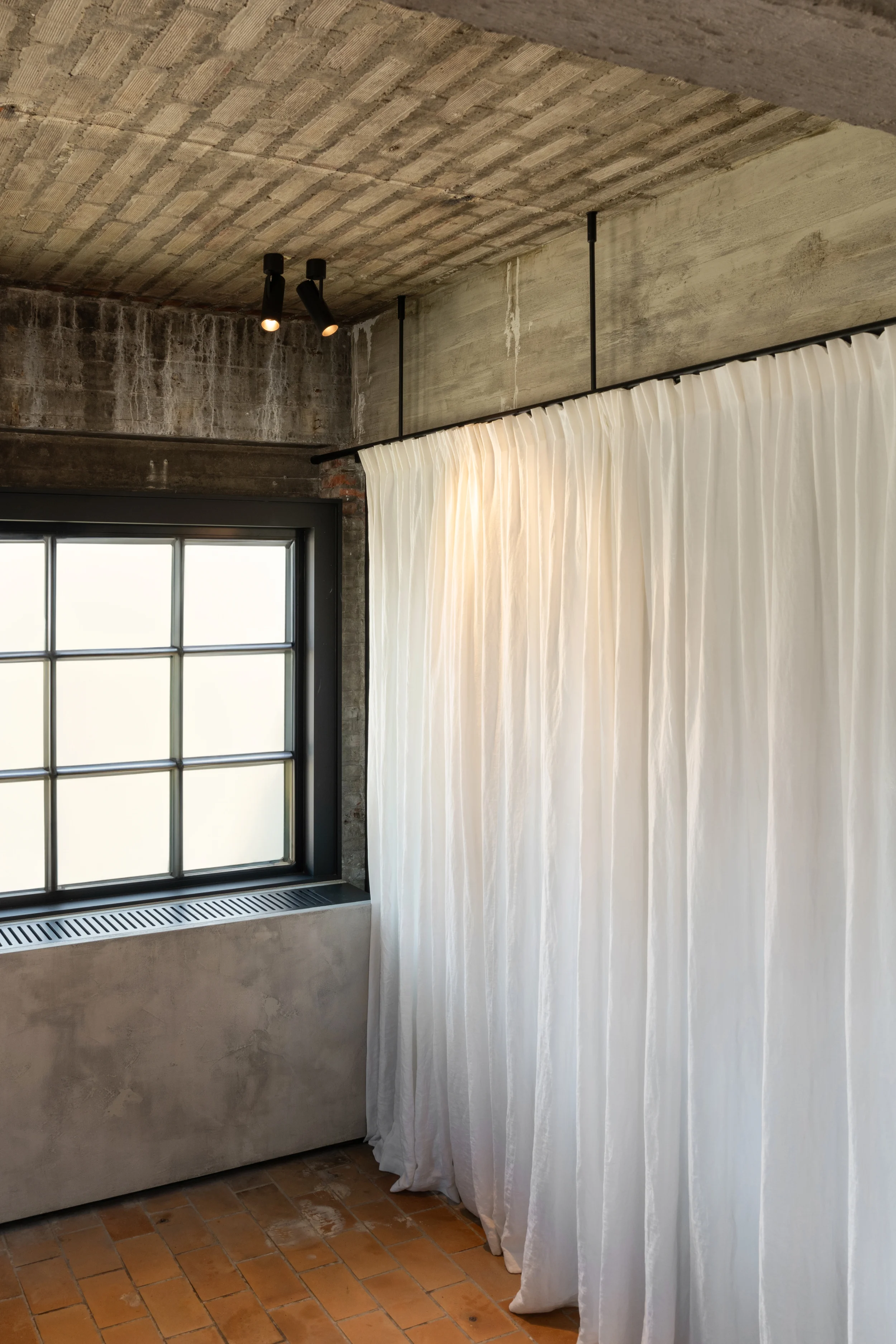 Black Kreon Holon 60 Directional Surface spotlights in a concrete room with steel window and linen curtain