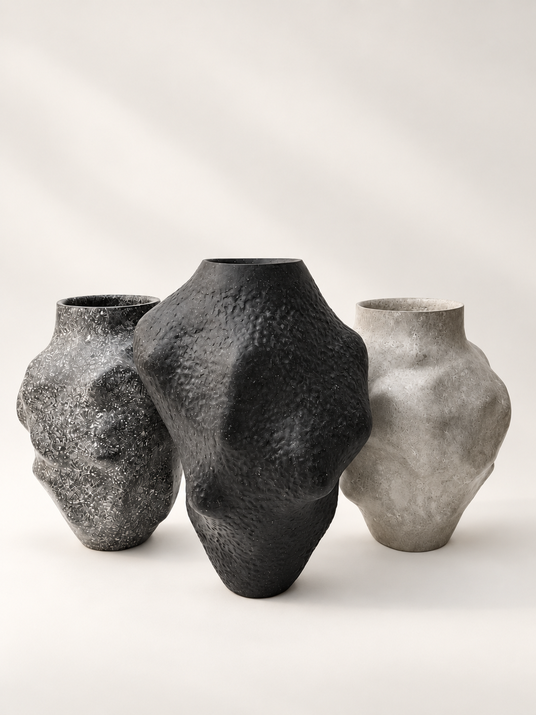 Three hand-sculpted recycled paper vases in speckled black, matte black and light grey by Justino Del Casar