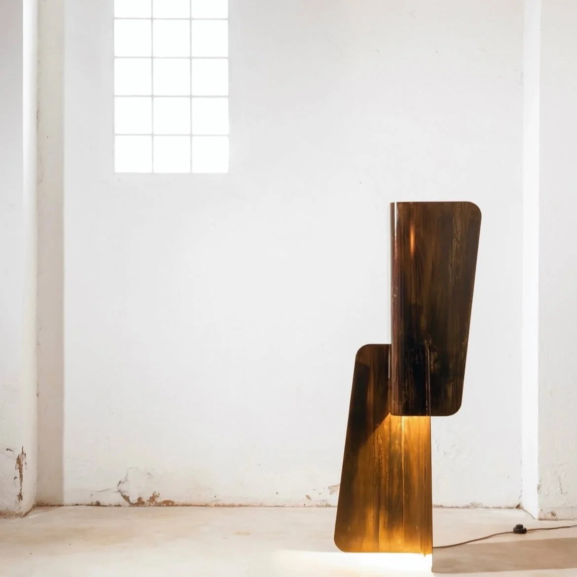 Sculptural standing lamp in brushed metal with cascading geometric forms, high-end interior lighting.