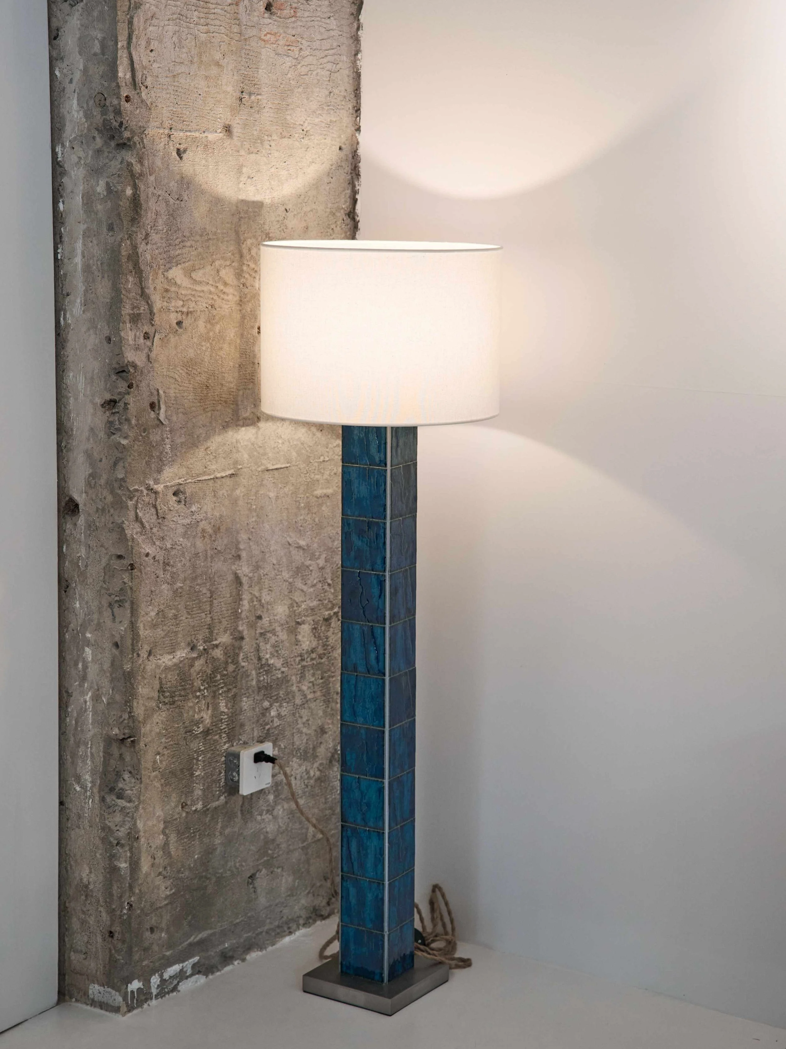 Sculptural floor lamp featuring sapphire-blue tiles and warm diffused light.