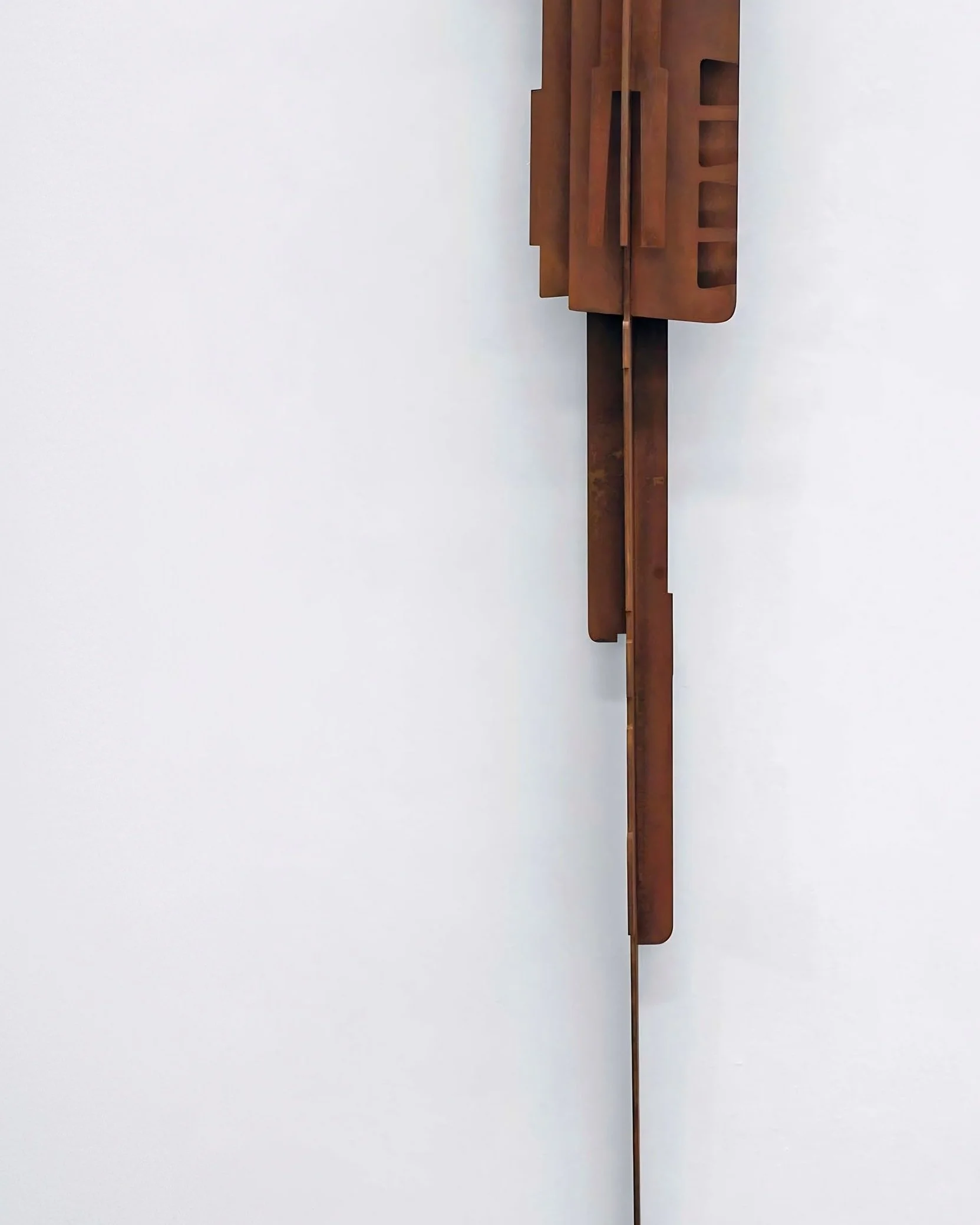 Outdoor and indoor corten steel totem sculpture, Composition Totem N8, presented against a minimal wall.