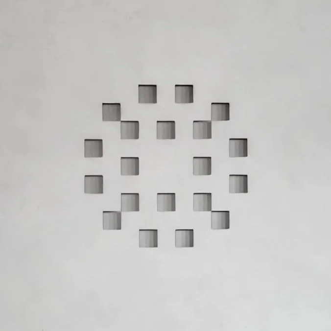 Contemporary white artwork by Robert Pous with light-responsive geometric voids and subtle visual movement.