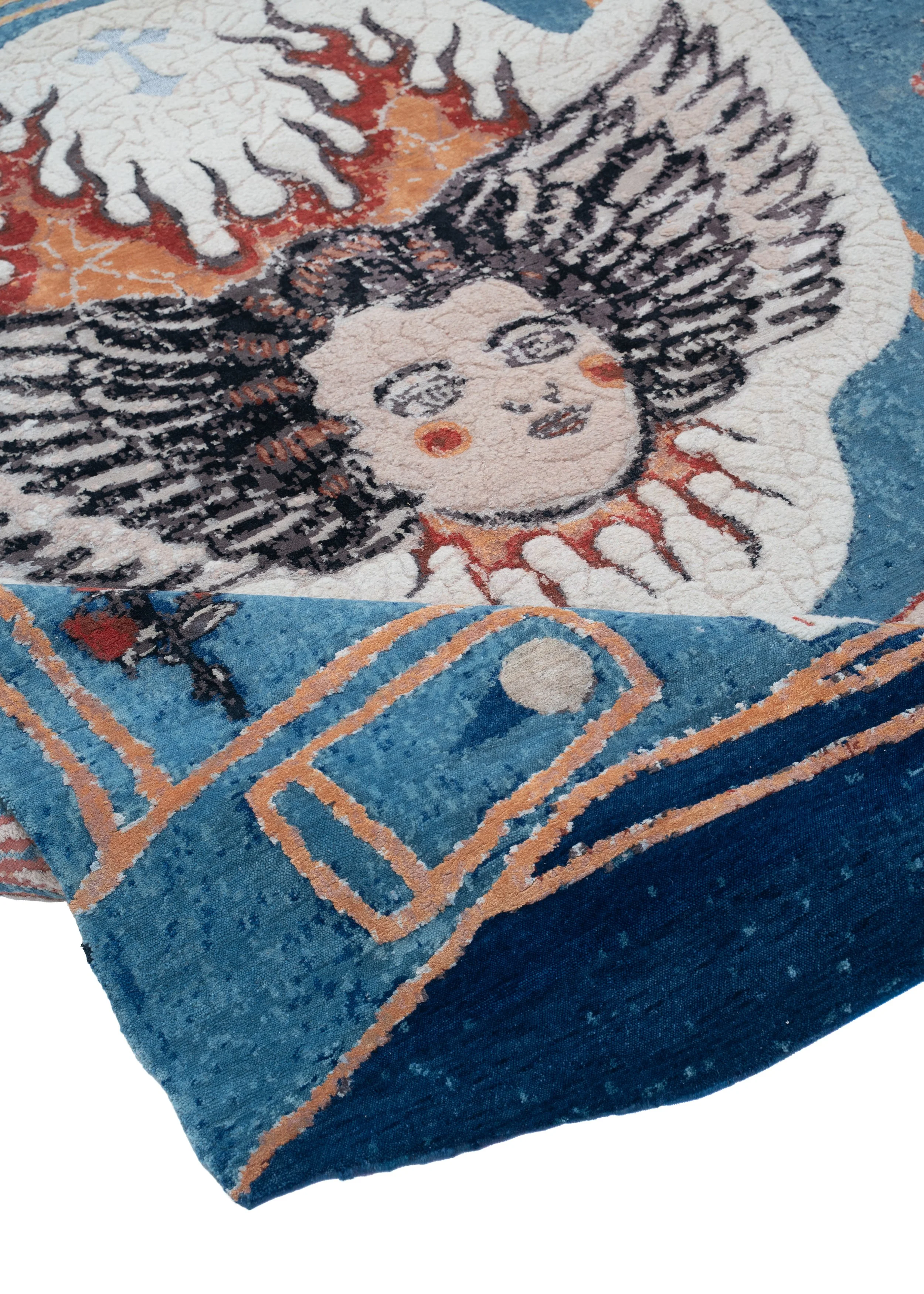 Close-up of Children of Sky by Julien Jaca folded over: hand-knotted wool and silk pile with angel face, flames and denim pocket