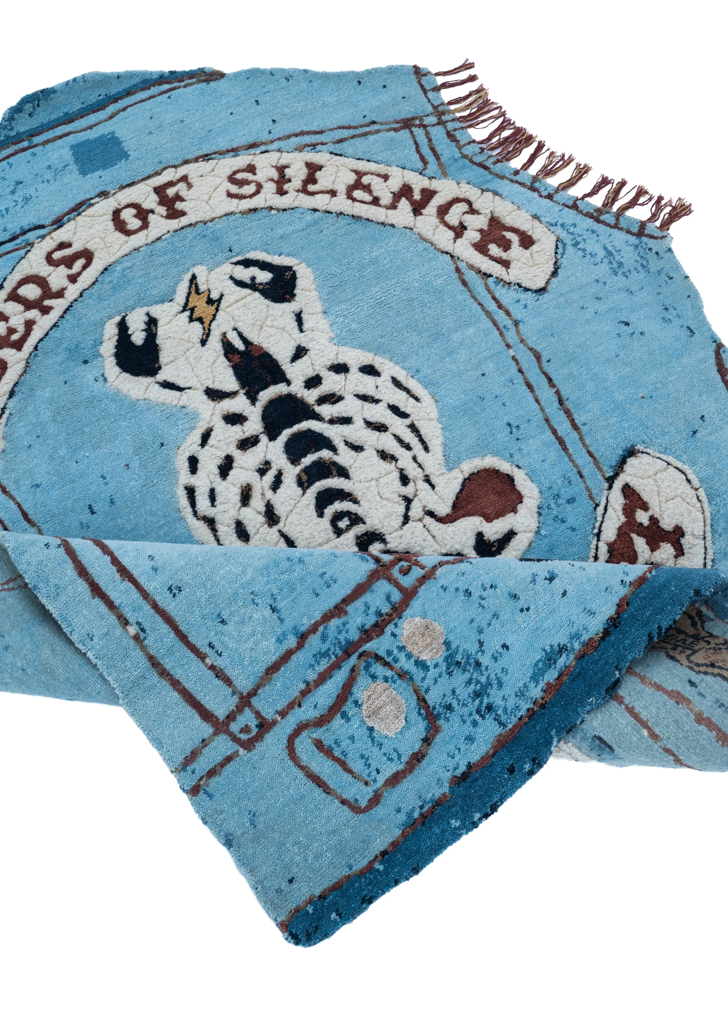 Close-up of Riders of Silence by Julien Jaca folded over: hand-knotted pile in wool, silk, alpaca and nettle with crackled scorpion patch