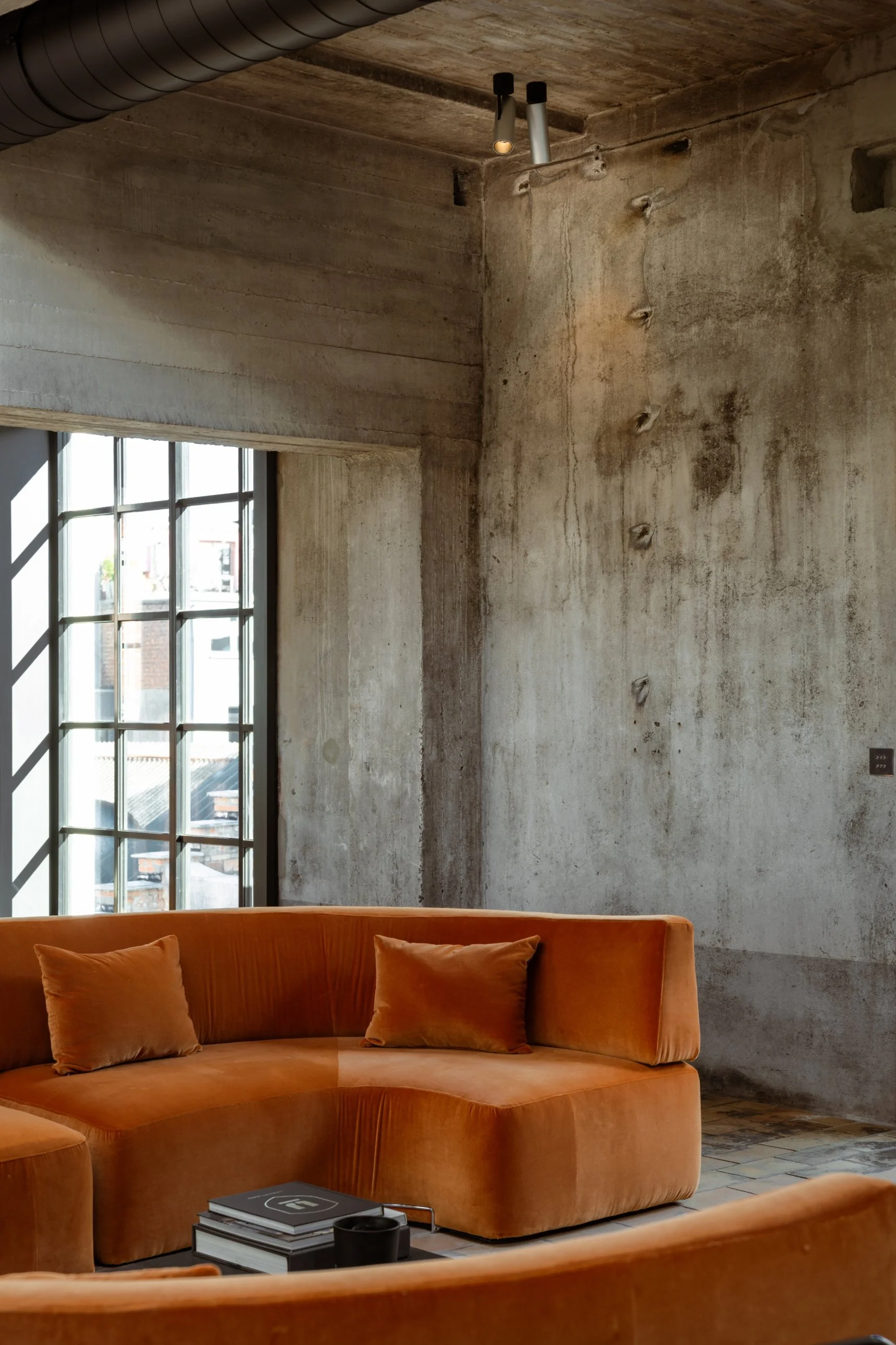 Kreon Holon 60 Directional Surface spotlights above a velvet sofa in an industrial concrete loft