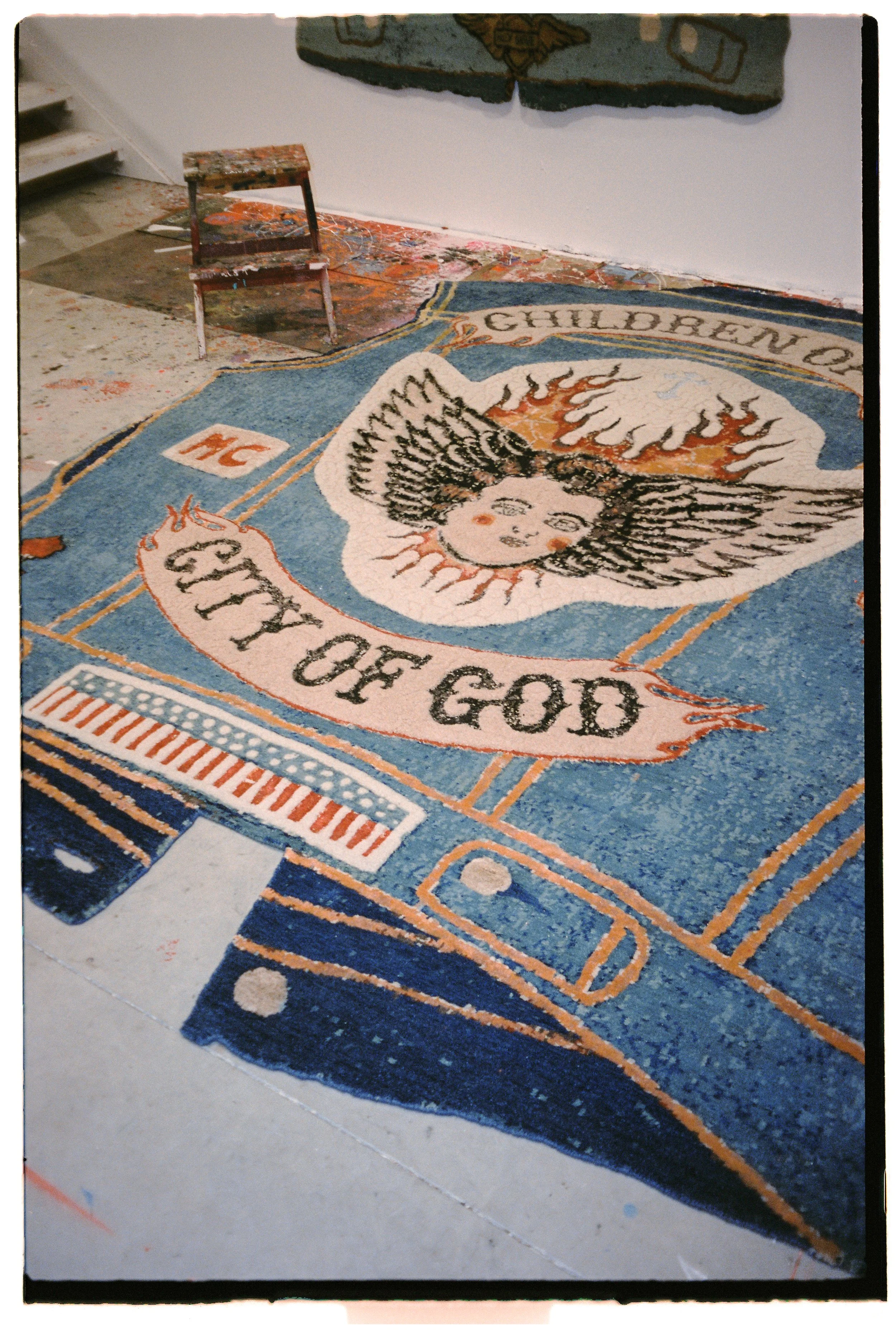 Children of Sky hand-knotted rug by Julien Jaca laid on the paint-splattered floor of the artist's studio, Dinodo Studio