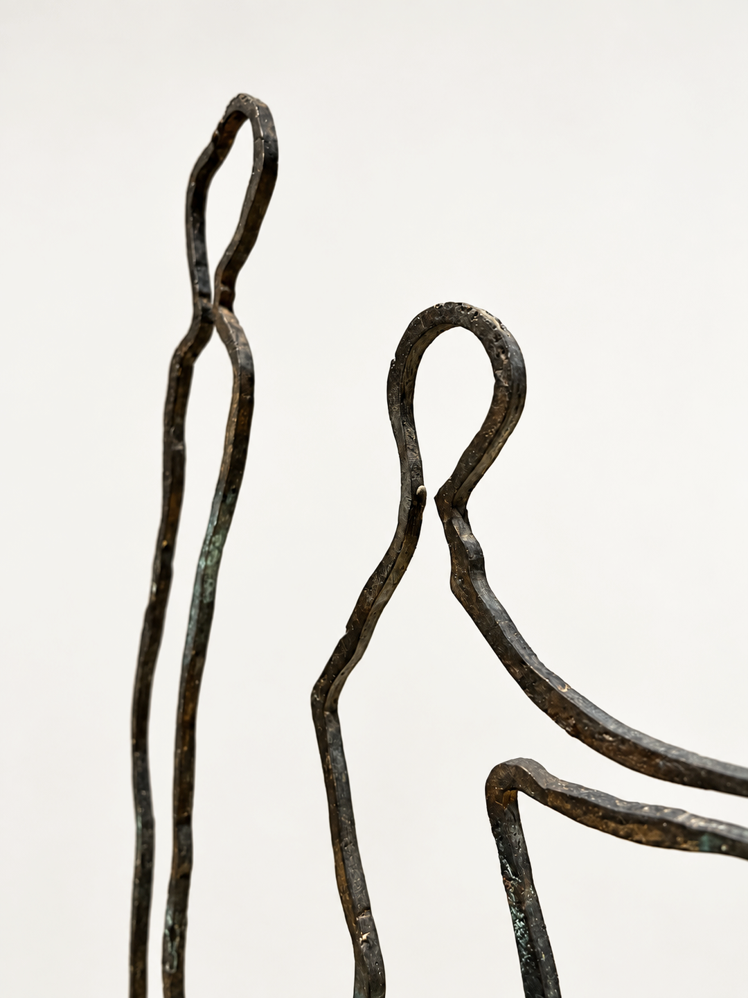 Close-up of the two bronze figures of Contact by Robert Pous showing hand-worked patina and texture