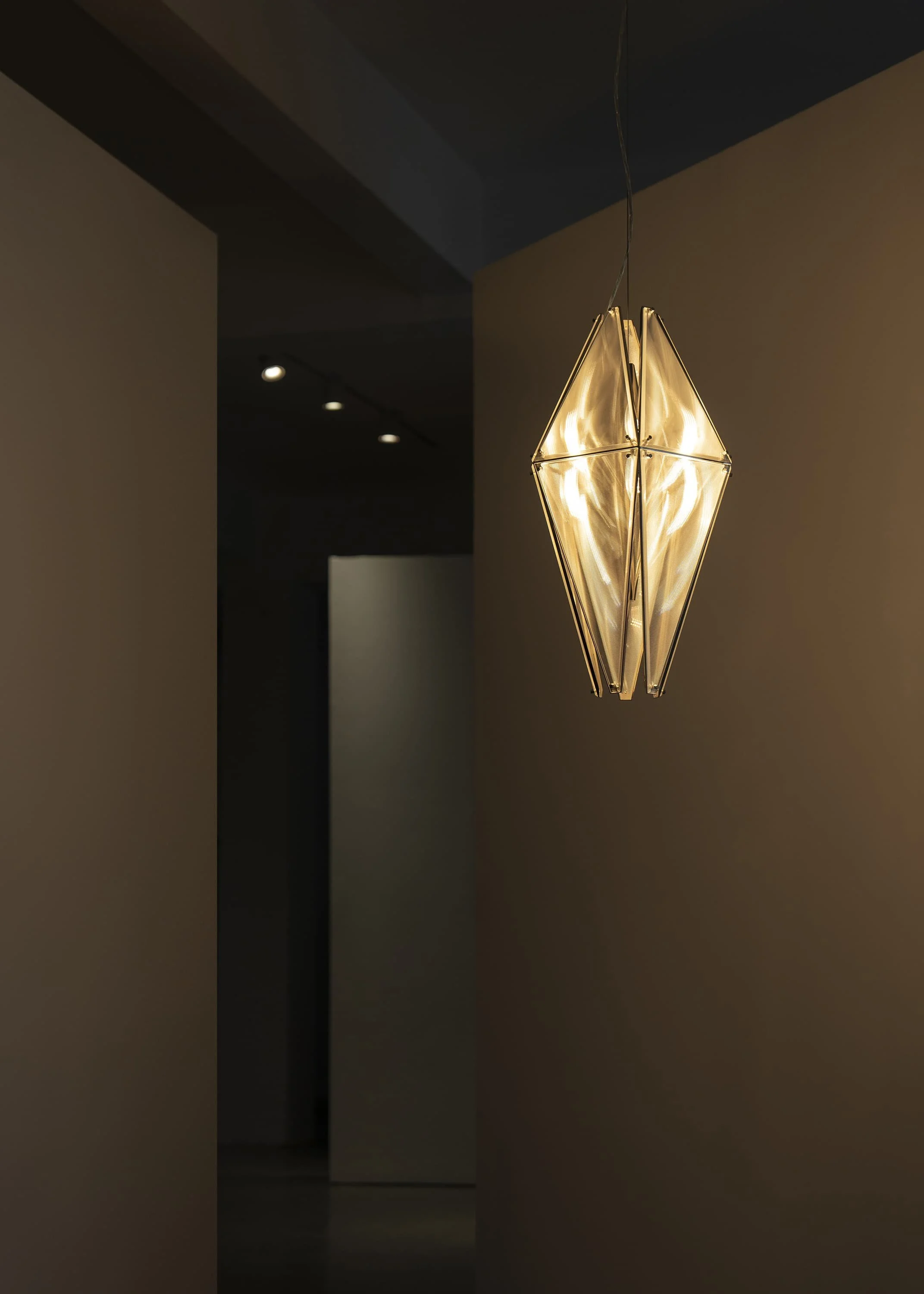 Sculptural hanging light combining precision structure and atmospheric illumination.