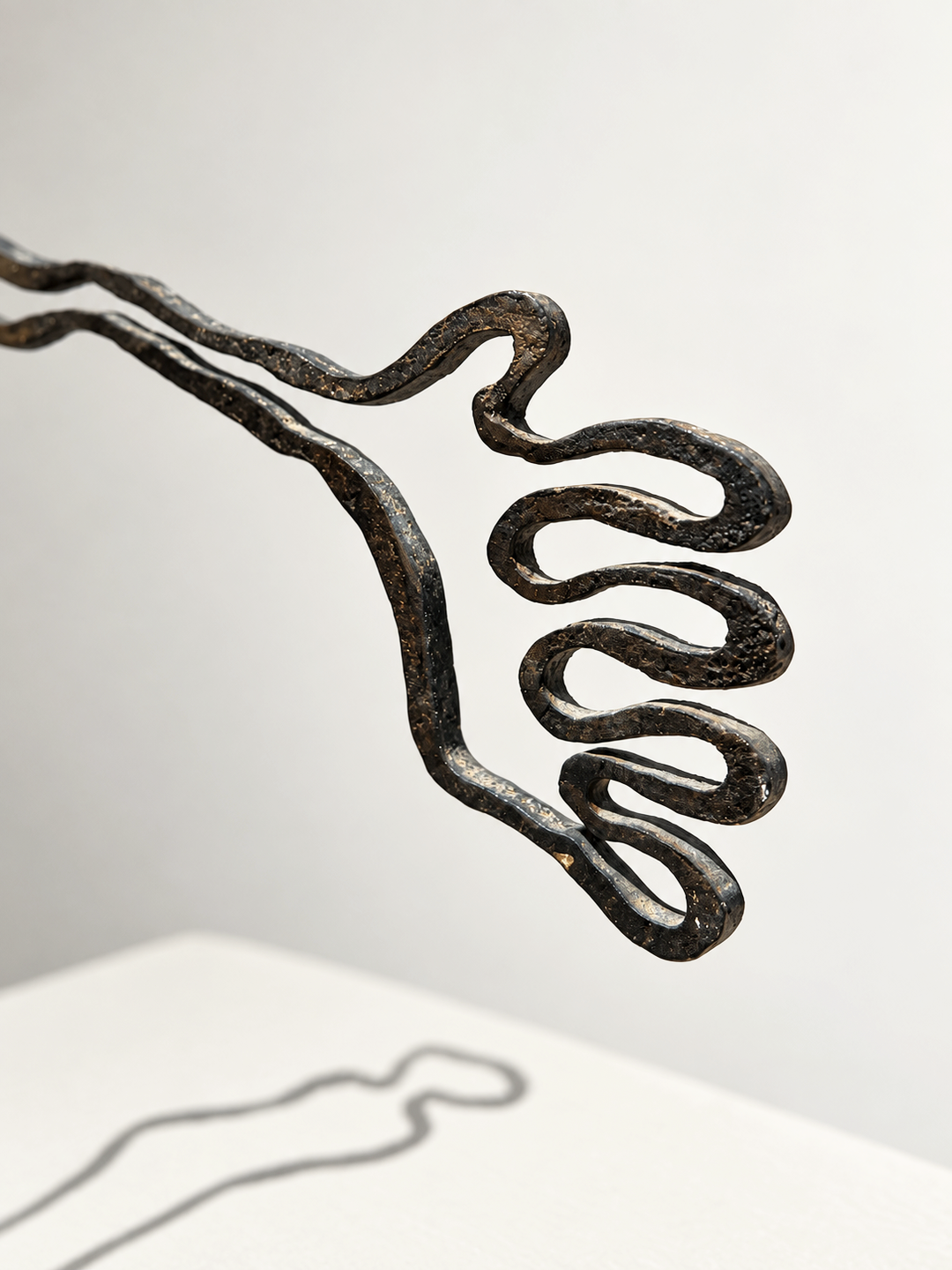 Detail of the outstretched hand of Contact, cast bronze line sculpture by Robert Pous