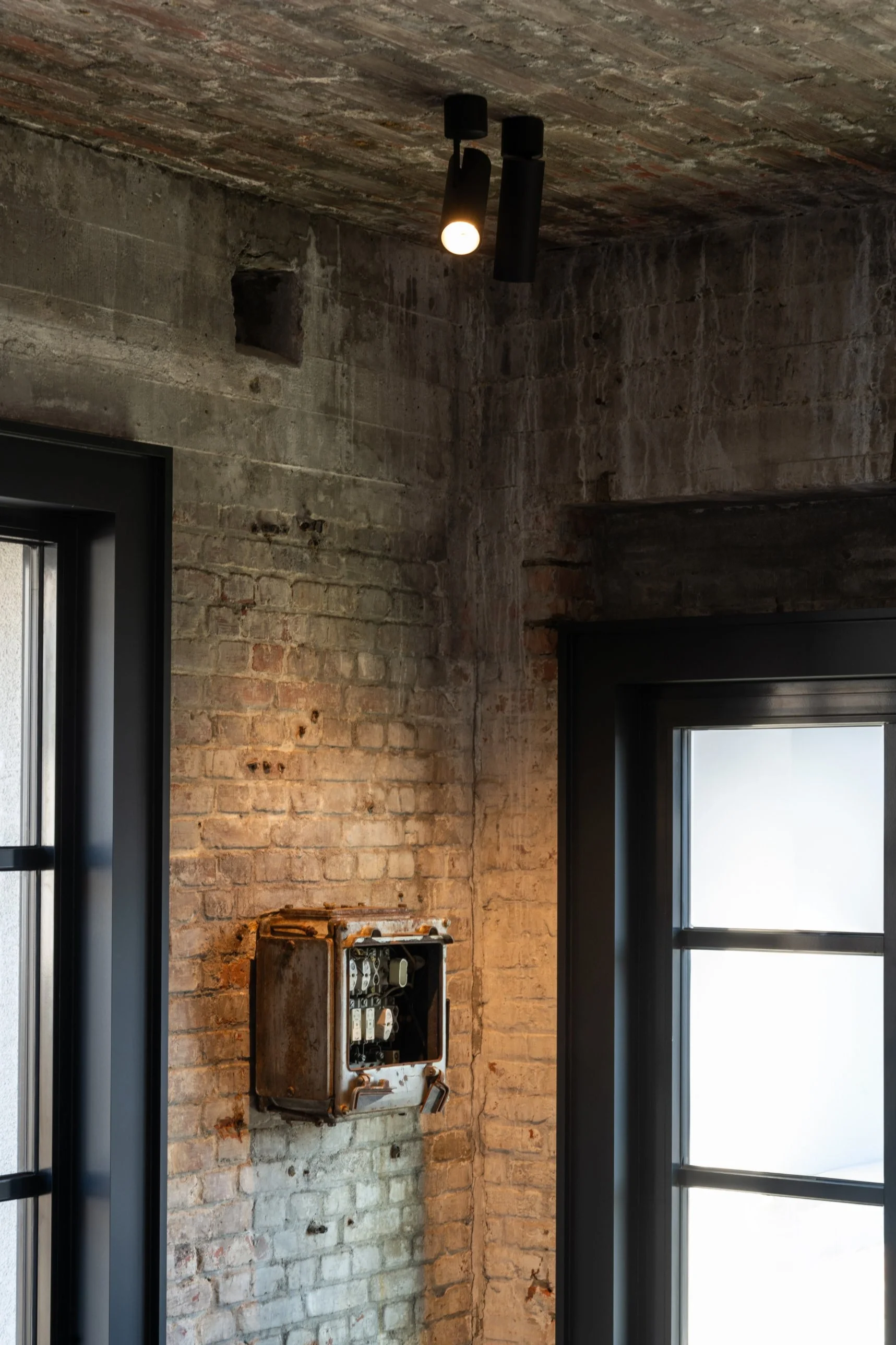 Black Kreon Holon 60 Directional Surface spotlights accenting an exposed brick wall in an industrial interior