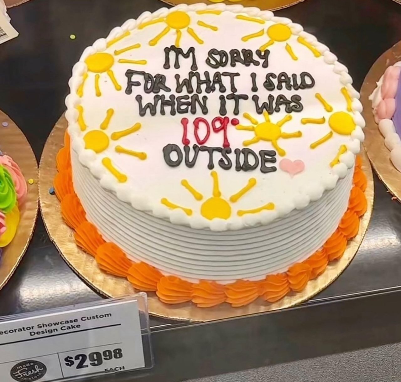 white cake with yellow, black, and orange frosting, cake reads "I'm sorry for what I said when it was 109 degrees outside"