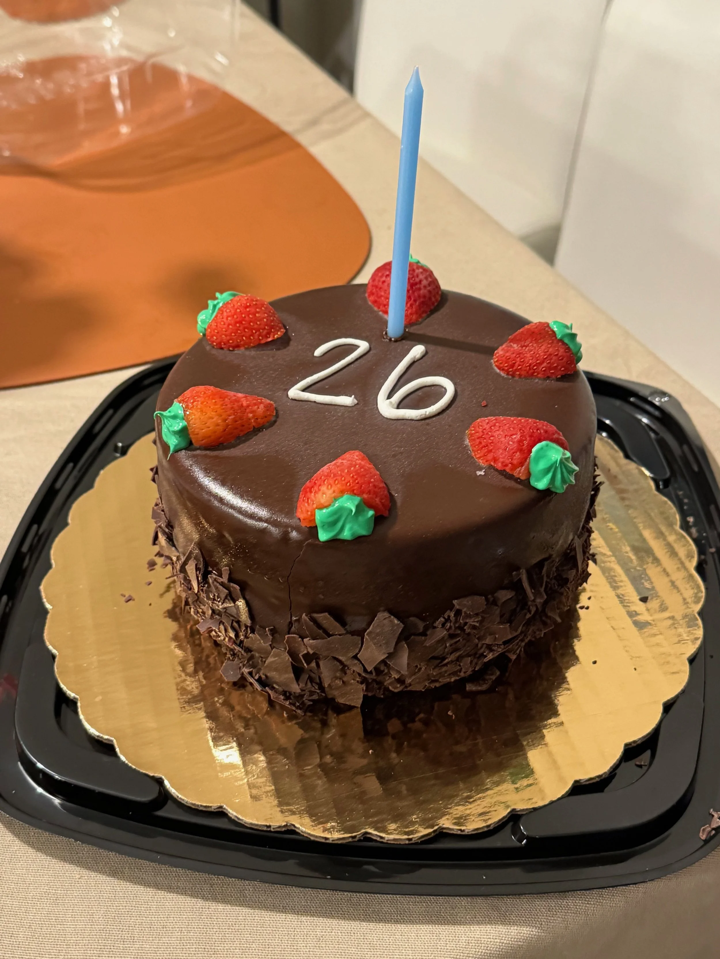 chocolate ice cream cake with frozen strawberries on the top, cake reads "26"