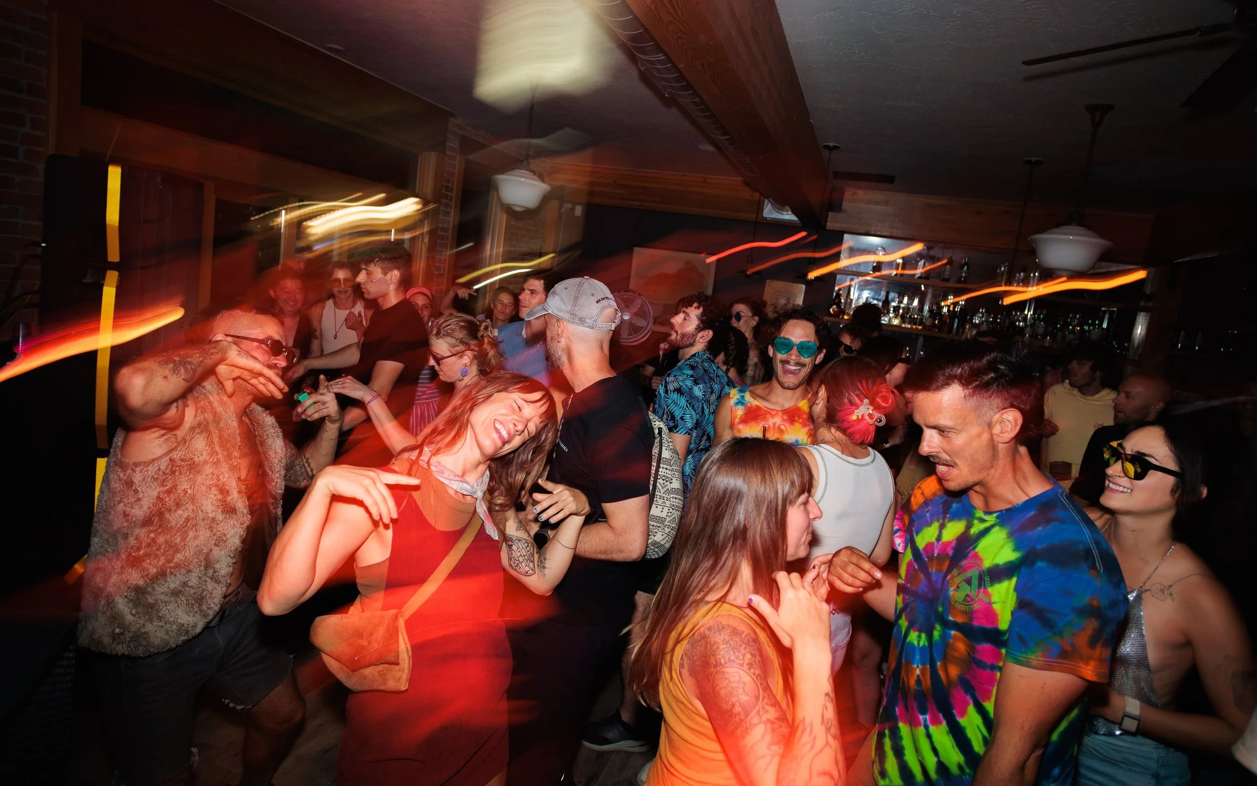 People dancing and having fun at a lively party or nightclub, with colorful lighting and a crowded, joyful atmosphere.