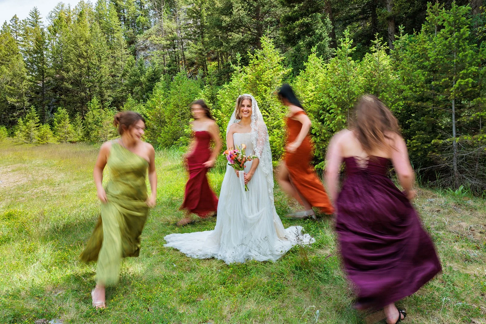 A wedding scene in a forest clearing with a bride in a white wedding dress holding a bouquet, surrounded by four women in colorful dresses dancing and moving around her.