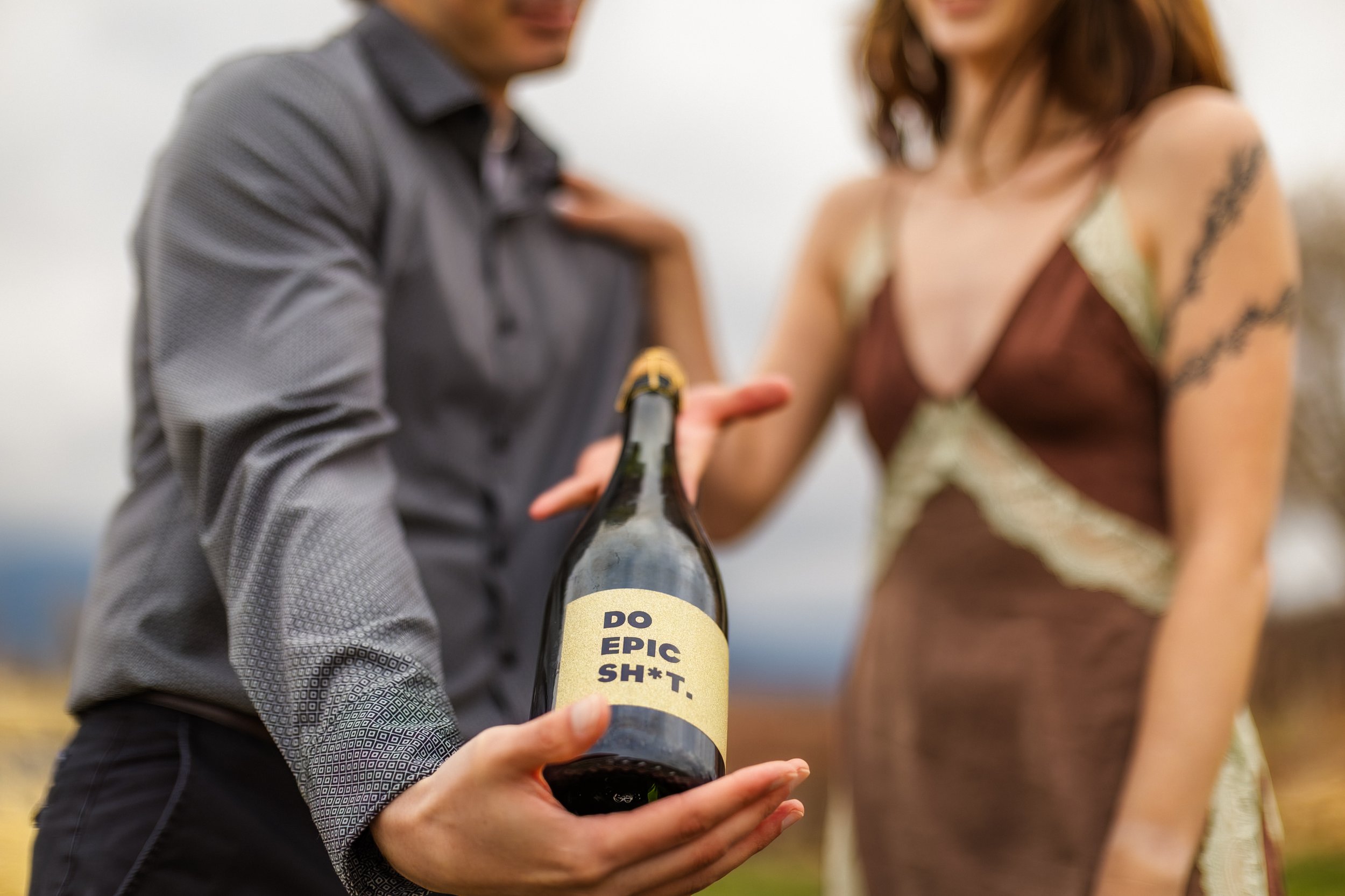 A man holding a bottle with a humorous label that reads 'Do Epic Sh*t'.