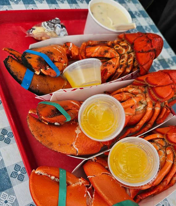 Fresh, boiled Maine lobsters served with cups of melted butter from Roy Moore Lobster Co. located at 39 Bearskin Neck in Rockport, Massachusetts