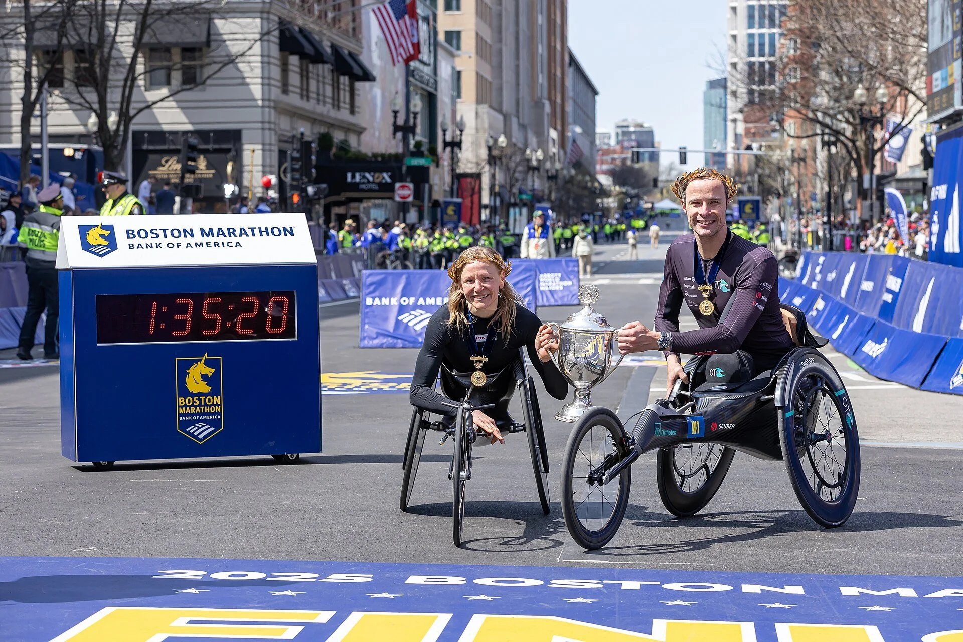 Wheelchair division winners Marcel Hug and Susannah Scaroni celebrating their victories at the 2025 Boston Marathon