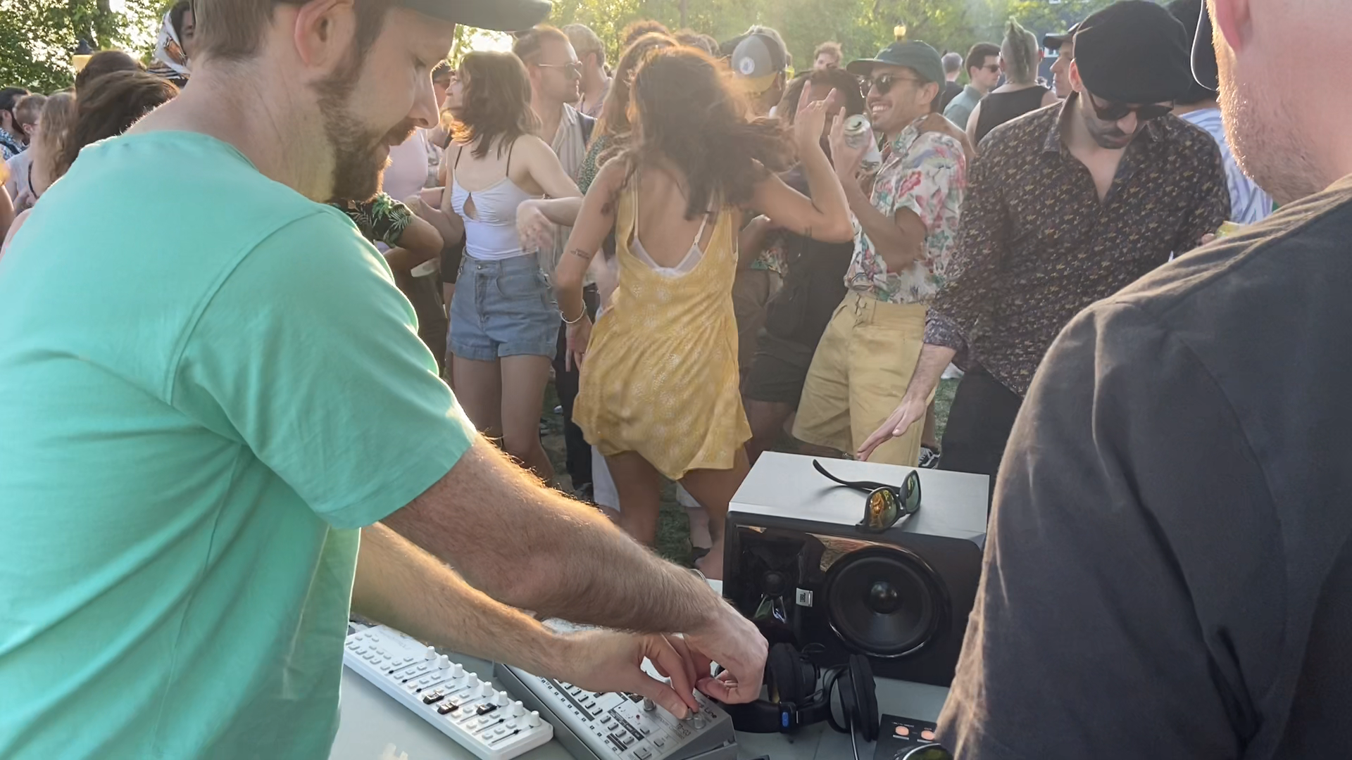 An outdoor DJ set with a crowd dancing in the sunlight.