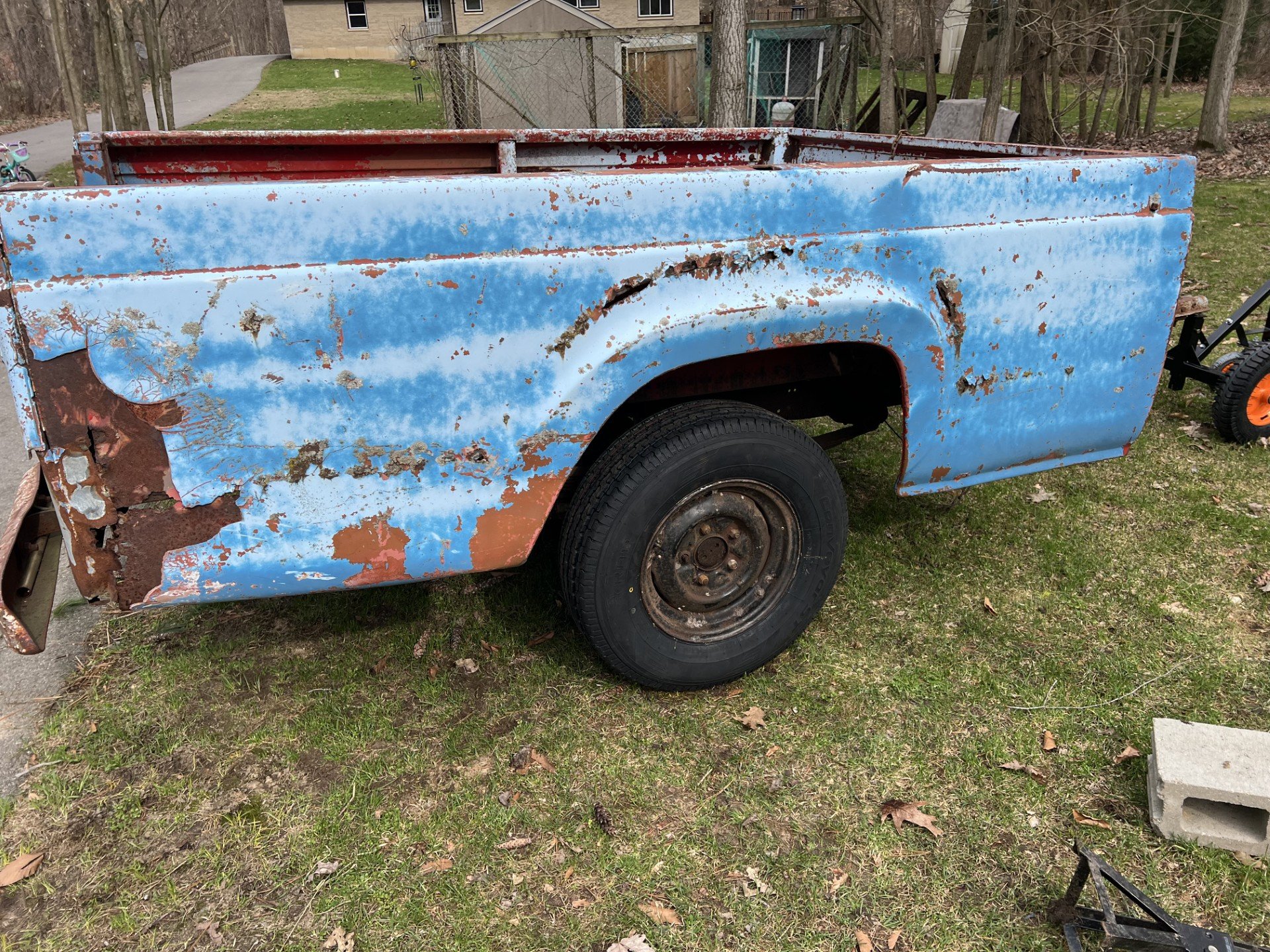 Rusty blue truck bed on grassy yard
