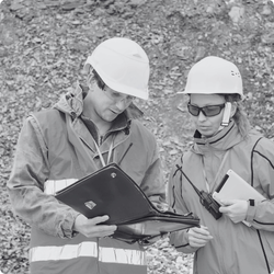 Two construction workers wearing safety helmets and jackets, looking at Aventa Solutions' operational readiness checklist whilst on site.