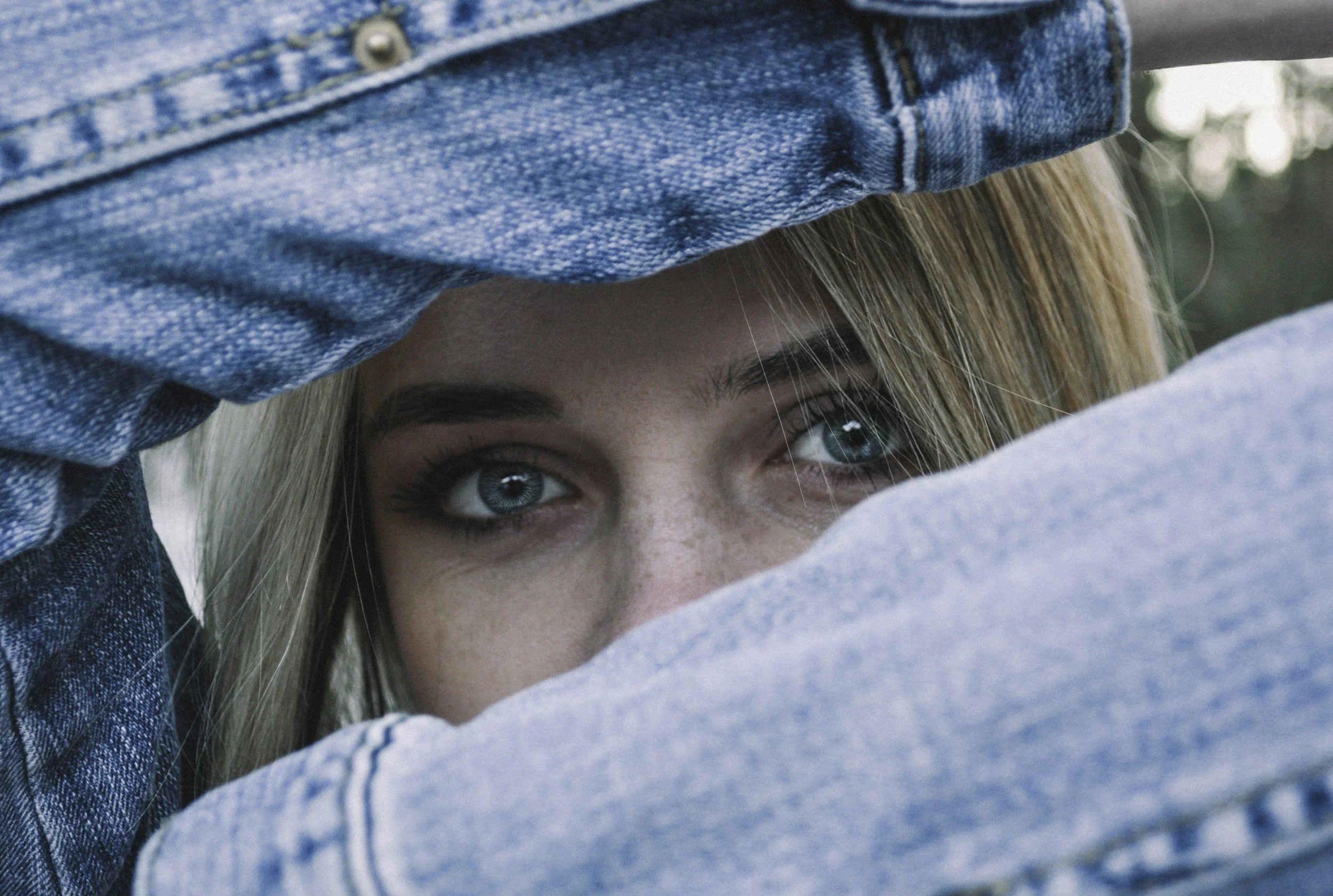 Woman family therapy participant peeking through arms in jean jacket