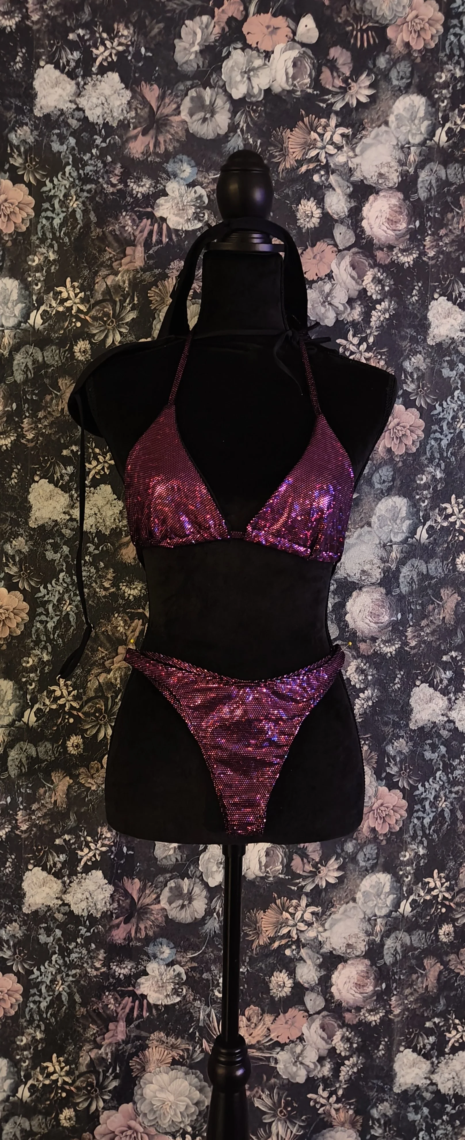 Mannequin wearing a purple sequin bikini against a floral background.