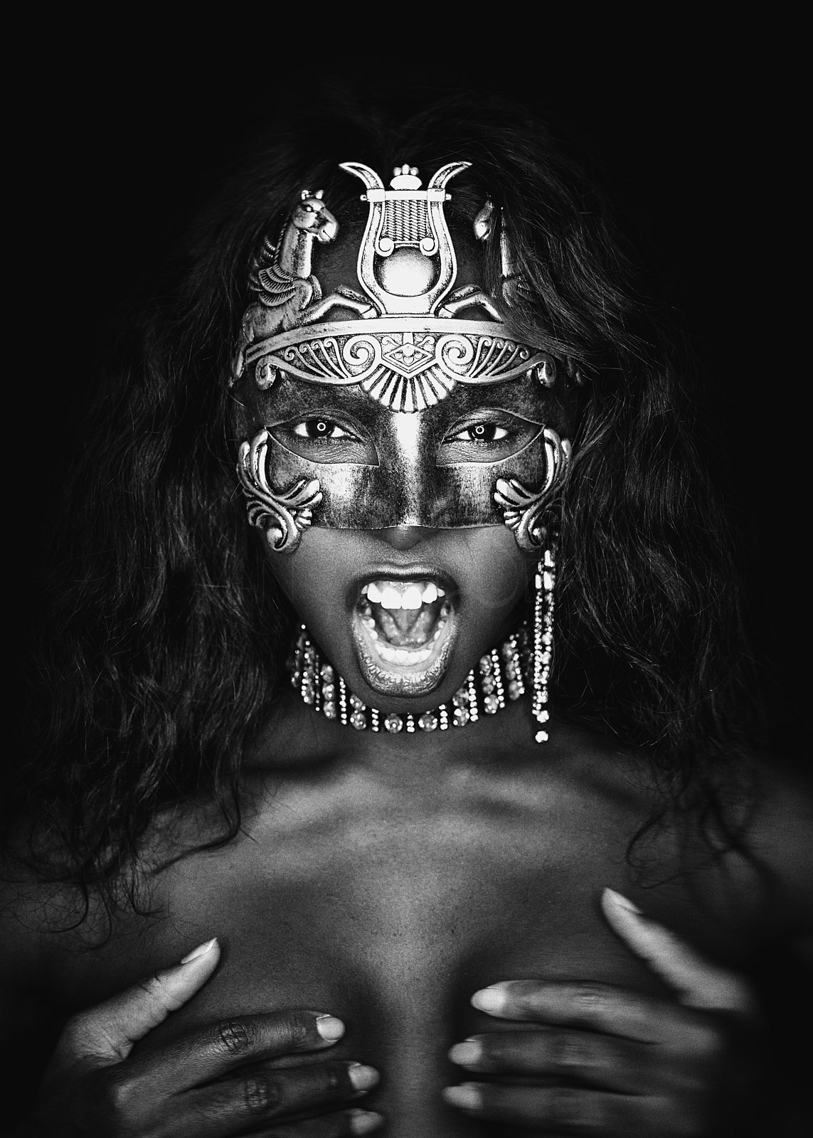 Schwarz-Weiß-Foto einer Frau mit offenem Mund, die eine kunstvolle Maske trägt und sich selbst bedeckt.