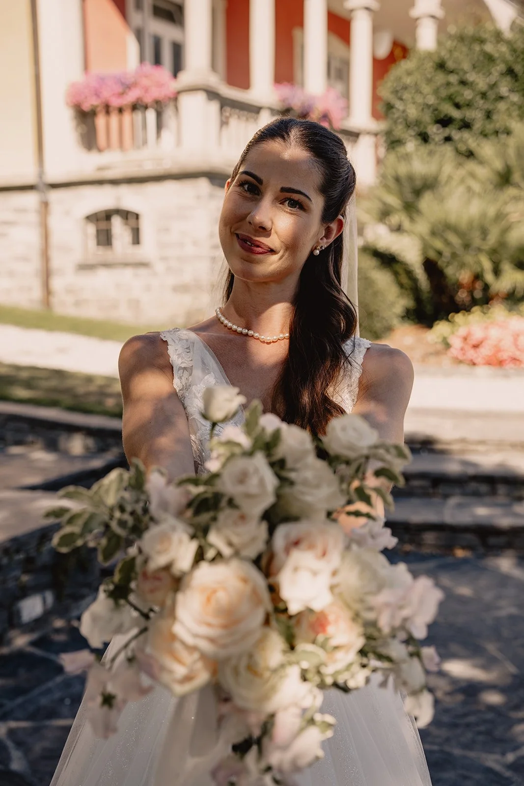 Braut in Hochzeitskleid mit Blumenstrauß im Freien, lächelnd, bei Sonnenlicht