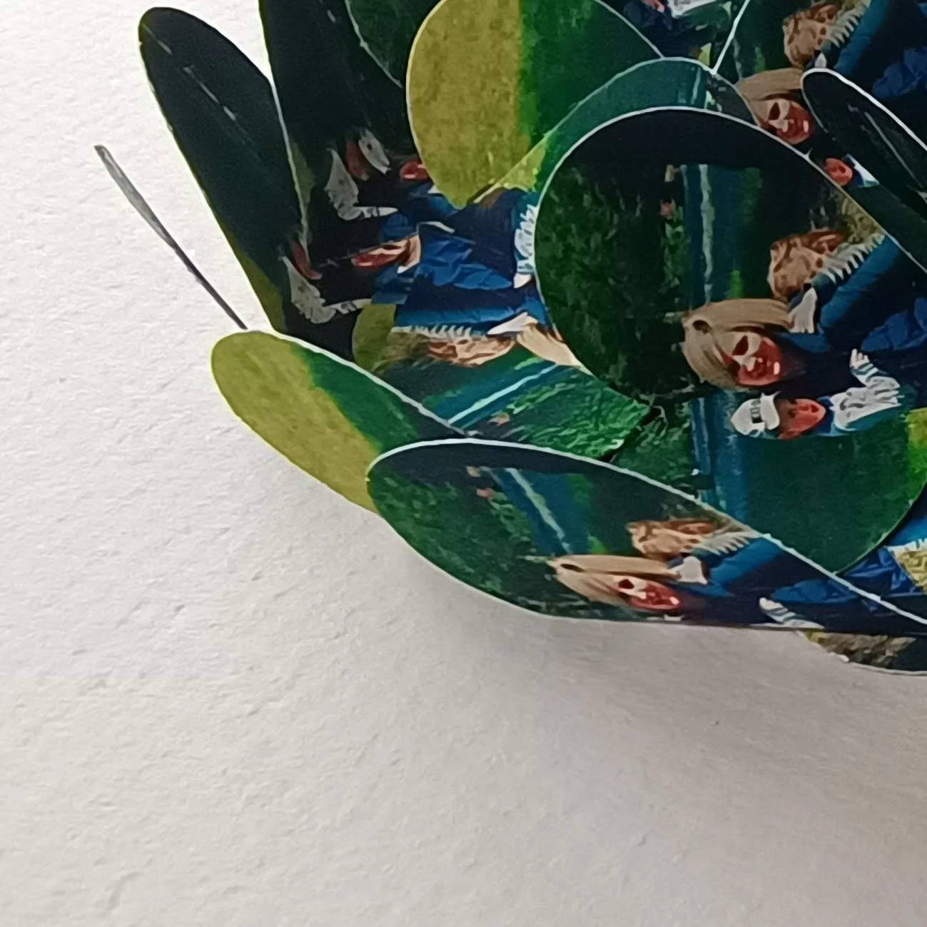 Close-up of a collage made from multiple printed photo hearts, featuring people in outdoor settings wearing casual clothing.