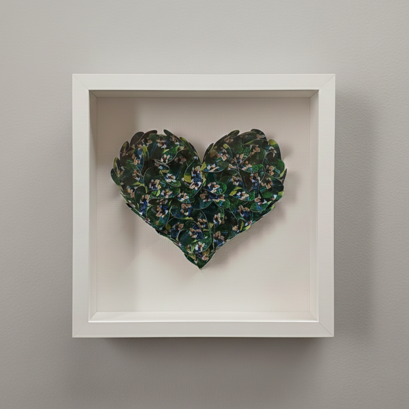 A framed heart-shaped picture hanging on a grey wall.