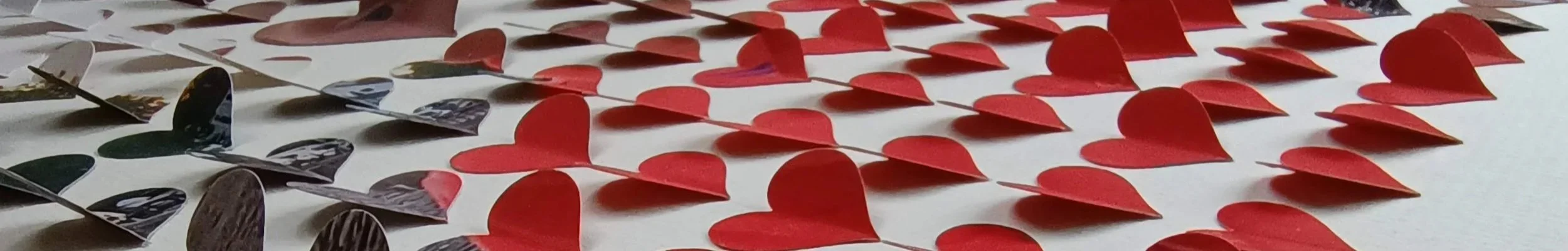 Multiple red paper hearts arranged in a pattern on a white surface.