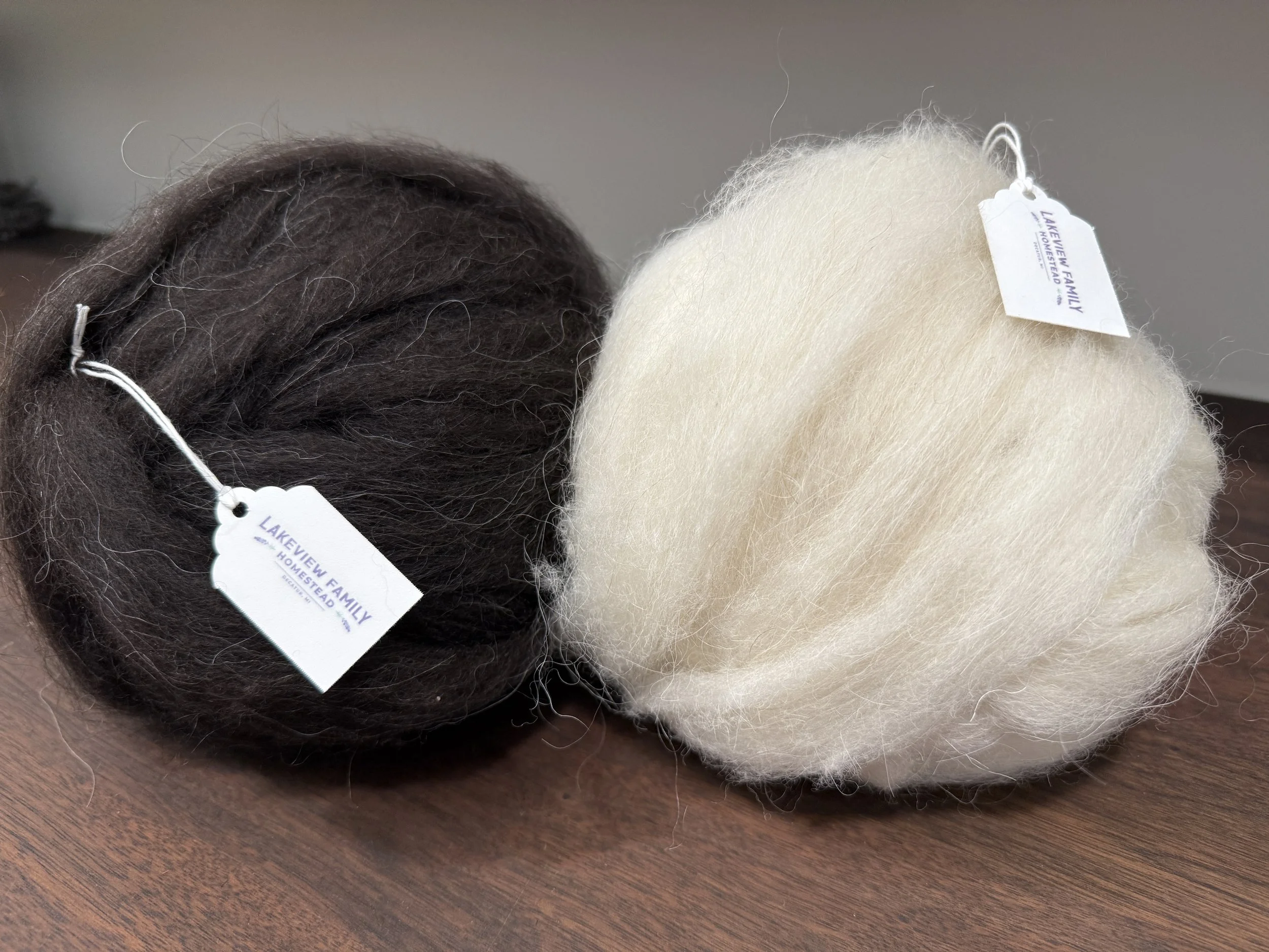 Two balls of Icelandic wool roving, one black and one white.