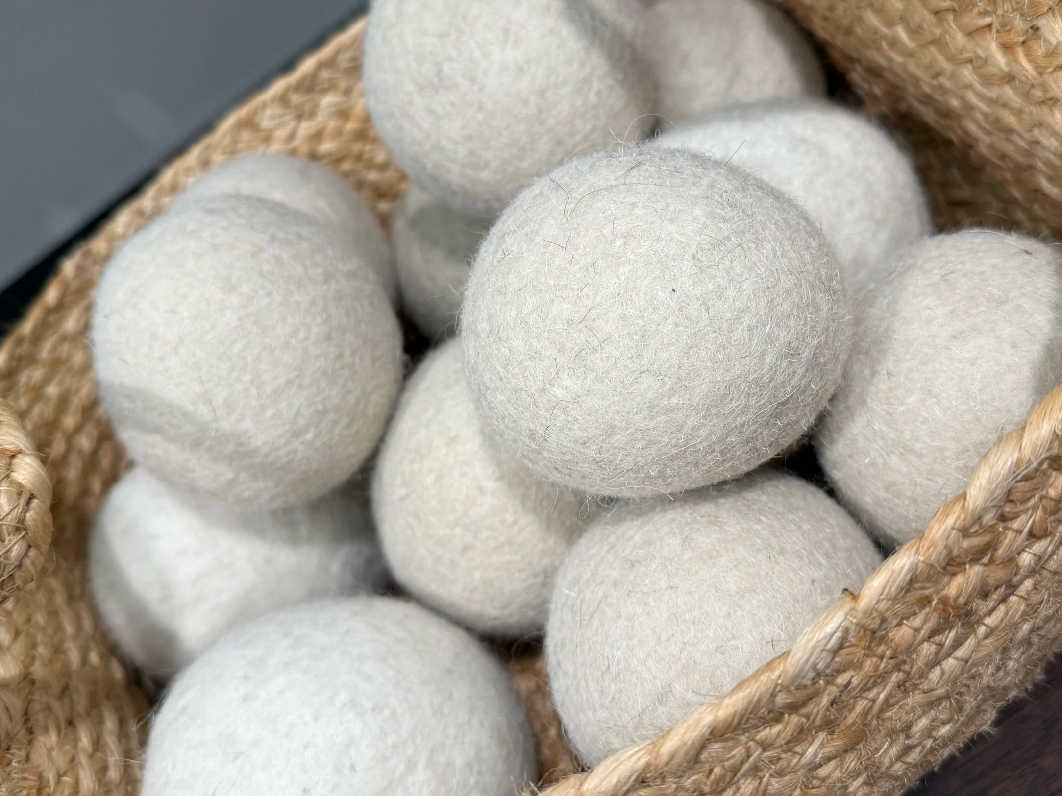 White felted wool dryer balls in a woven basket.