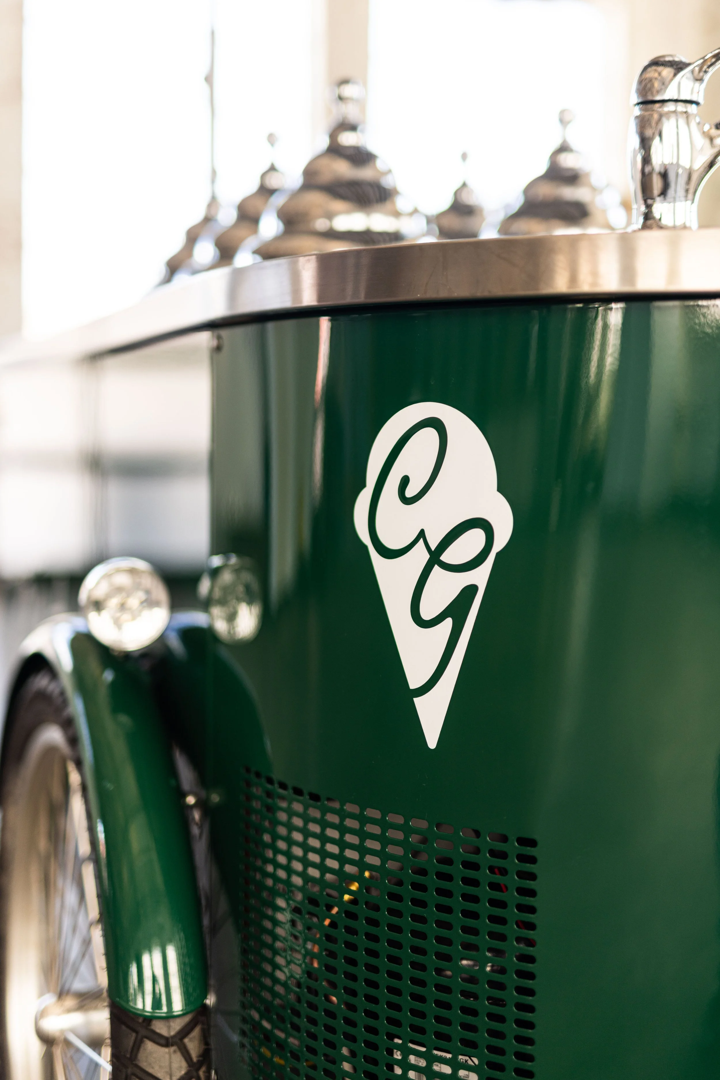Close-up of a green gelato cart with a white gelato cone logo.