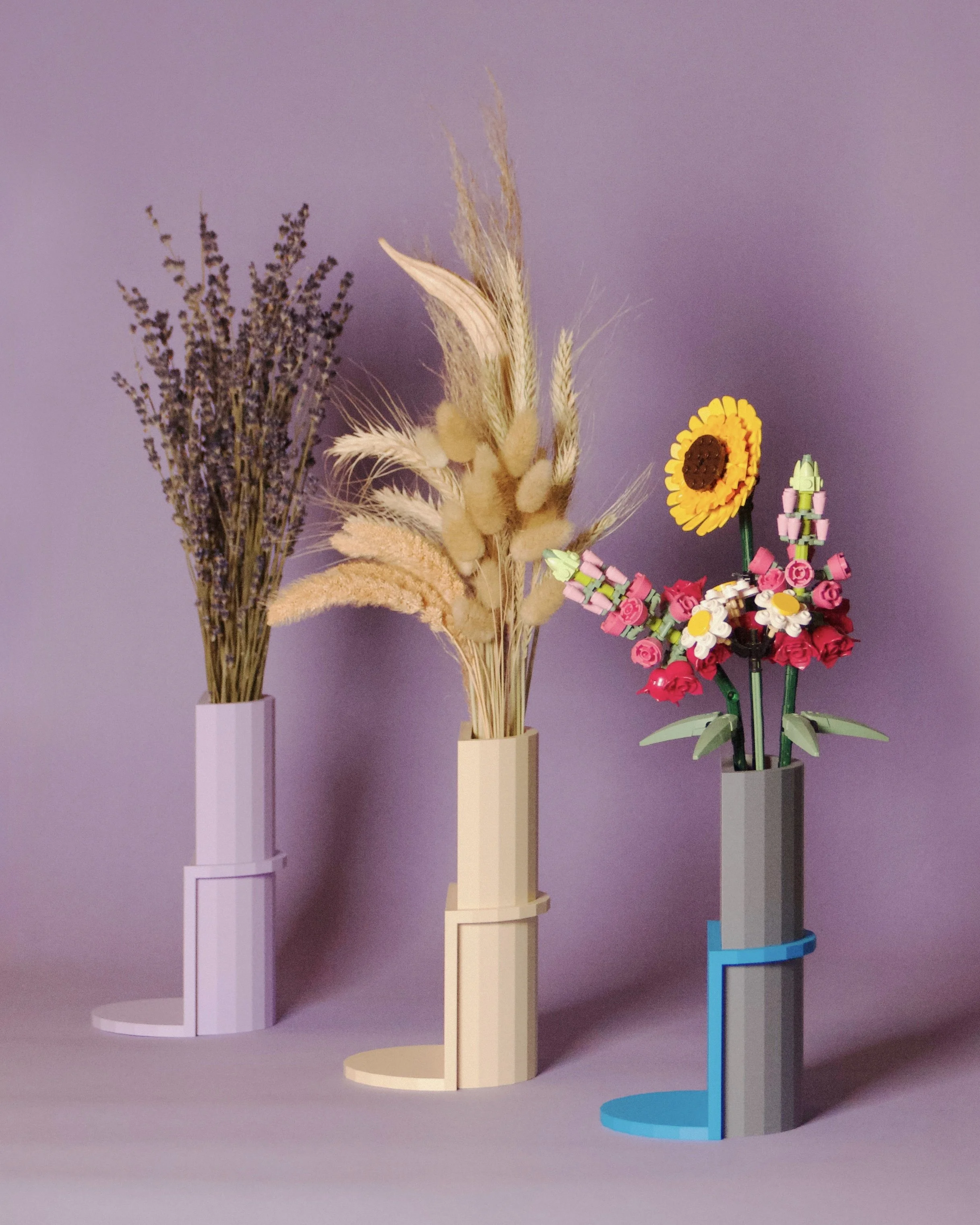Three vases with different arrangements of dried and artificial flowers against a purple background.