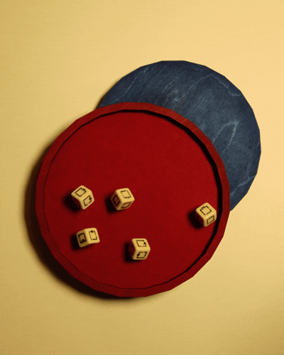 A red circular game board with five small lettered dice on it, placed on a yellow surface with a denim fabric in the background.