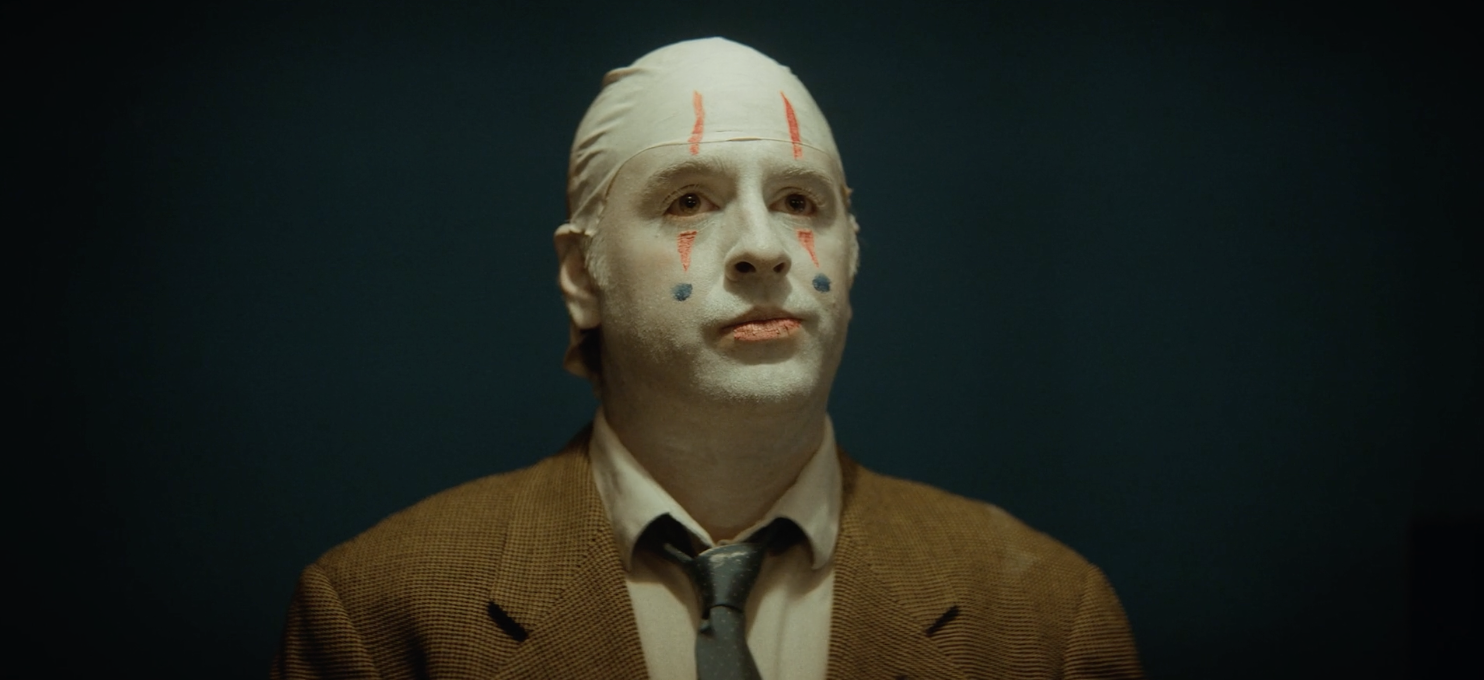 Actor Matt Walker stands proudly wearing clown makeup and a suit in a tamp based short film