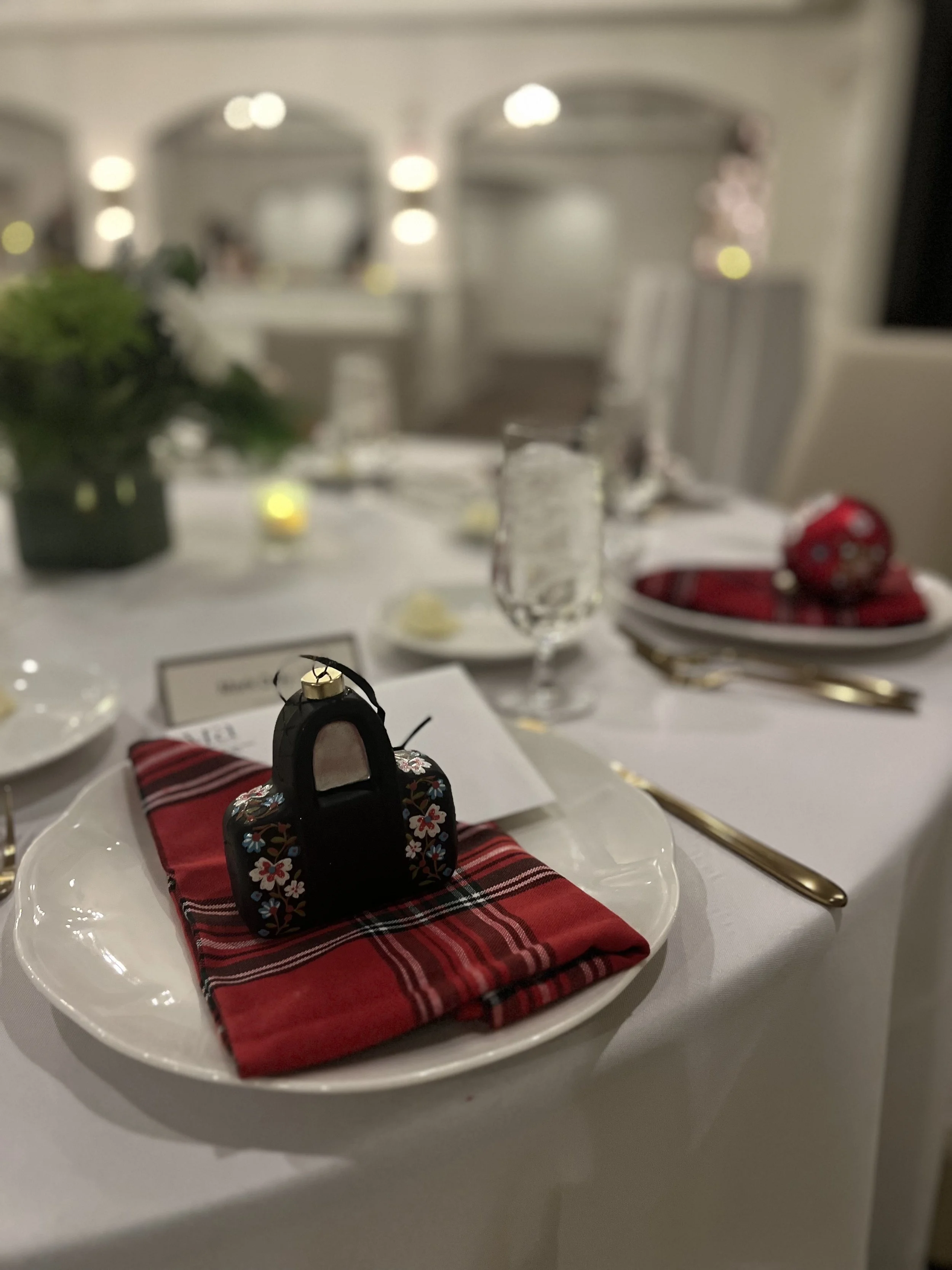 Buffet table with chafing dishes, decorative candles, greenery, and glass ornaments, illuminated by candlelight and outside lighting.