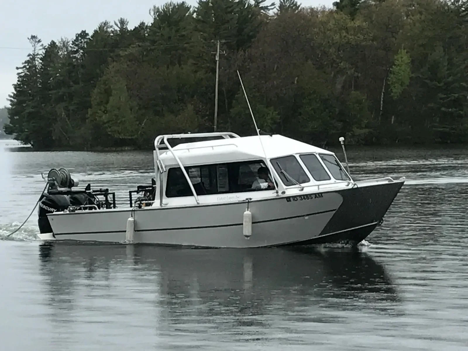 A small motorboat on North Twin Lake near the shoreline, part of the Eurasian Water Milfoil treatment.