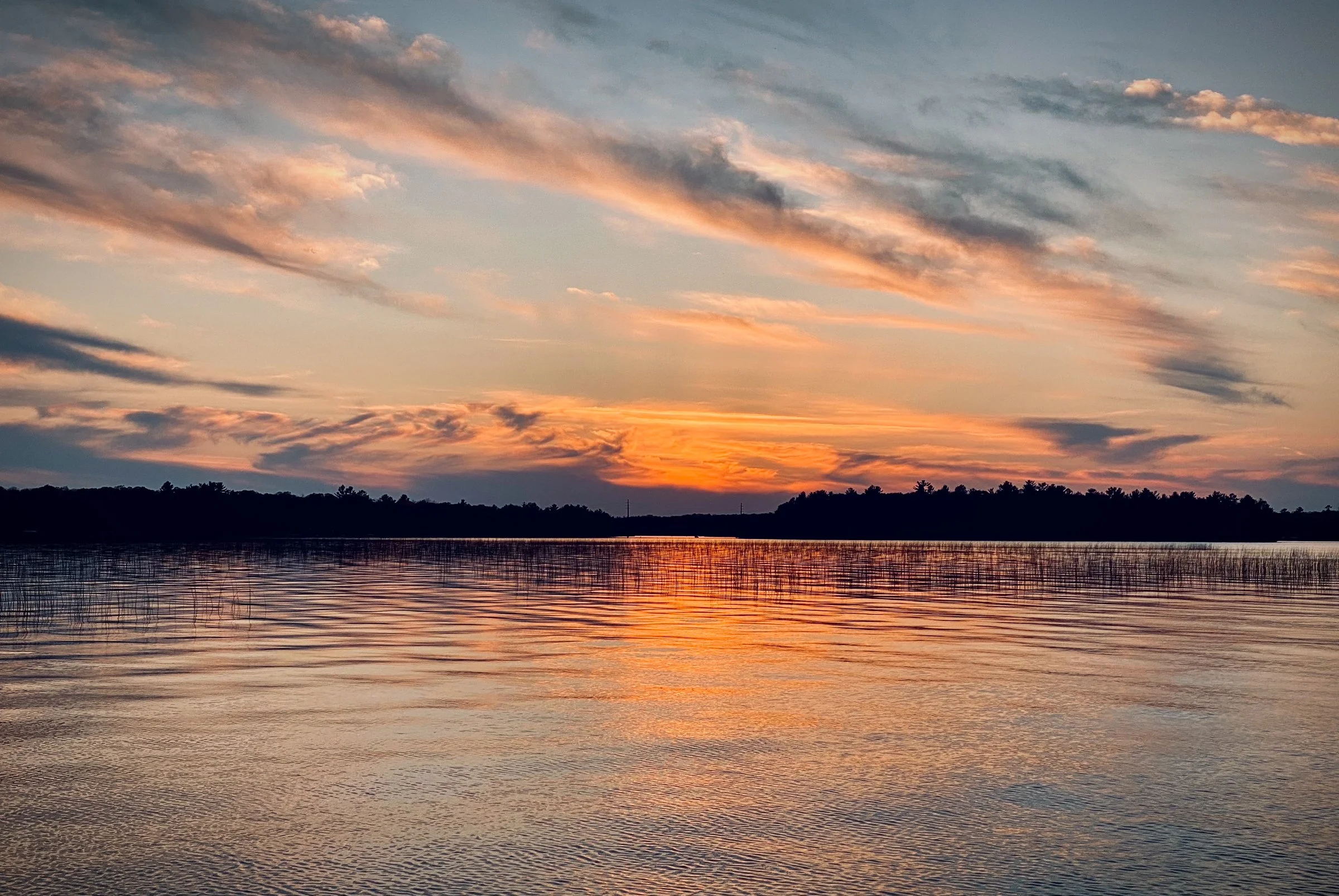 North Twin Lake at sunset with colorful sky and distant trees on the horizon.