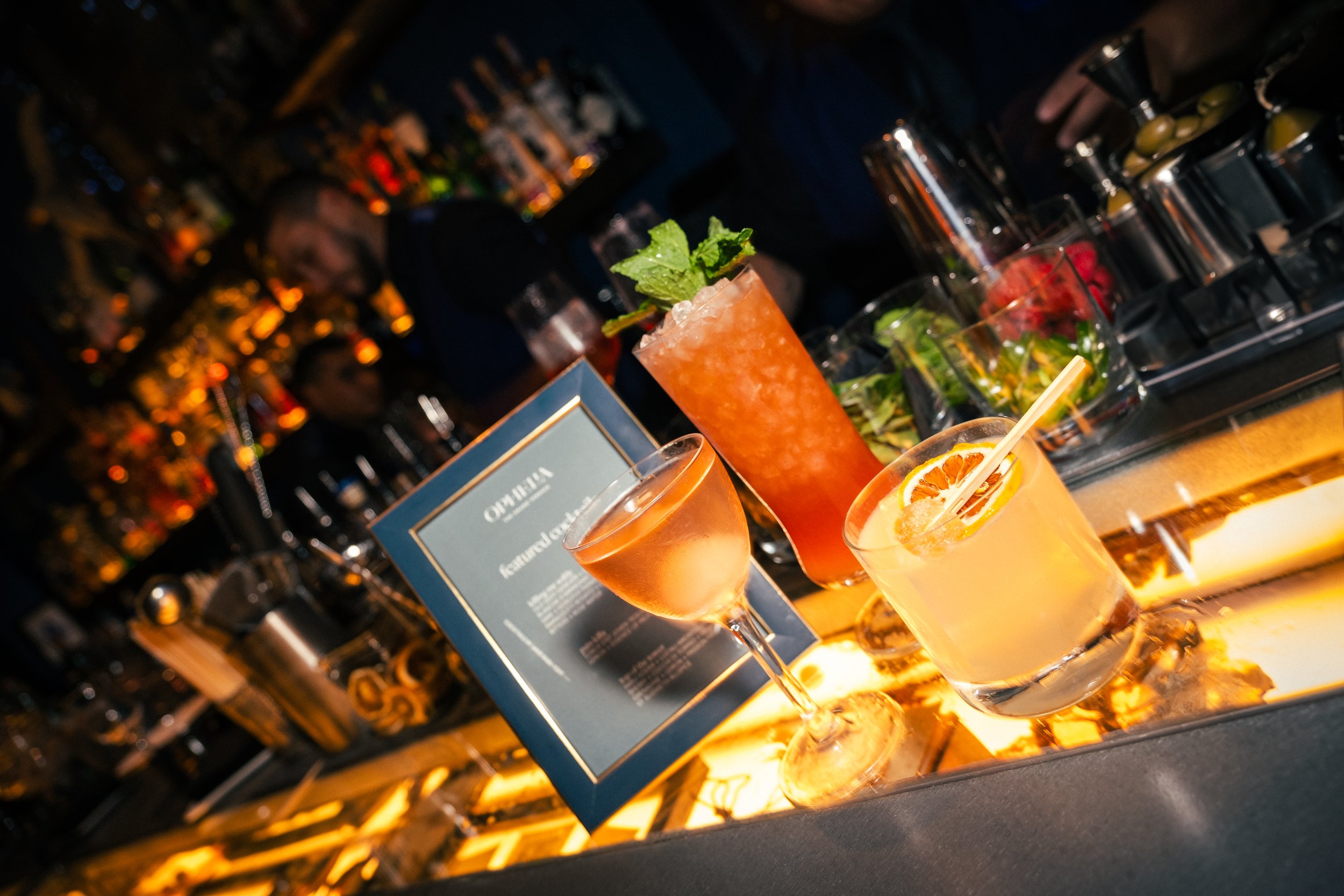 View of a city skyline with tall buildings and a bridge over a river, with people kayaking on the water during sunset.
