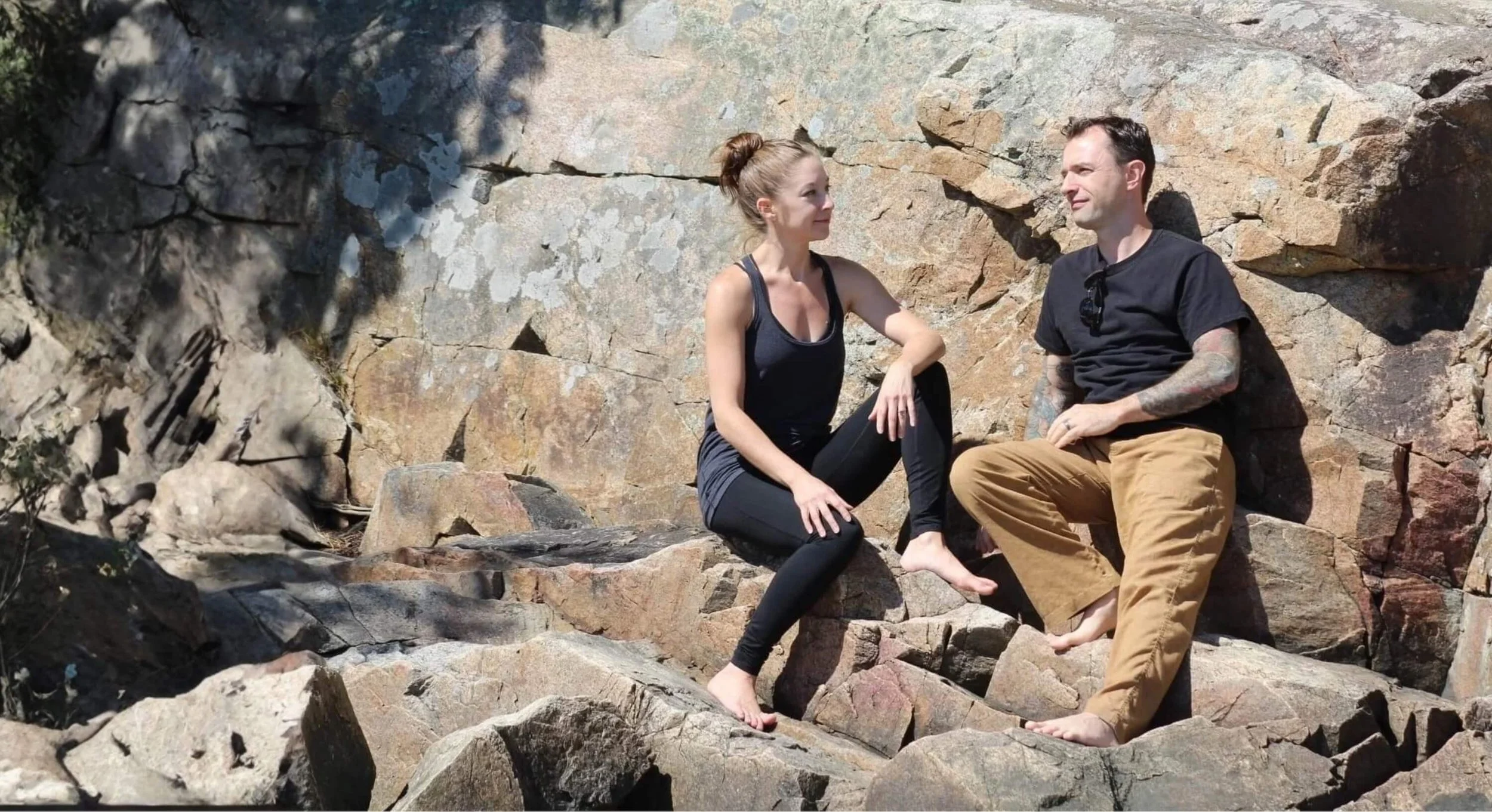 Ian Pullen, Cape Cod yoga instructor, sitting with his wife on a rocky coastline