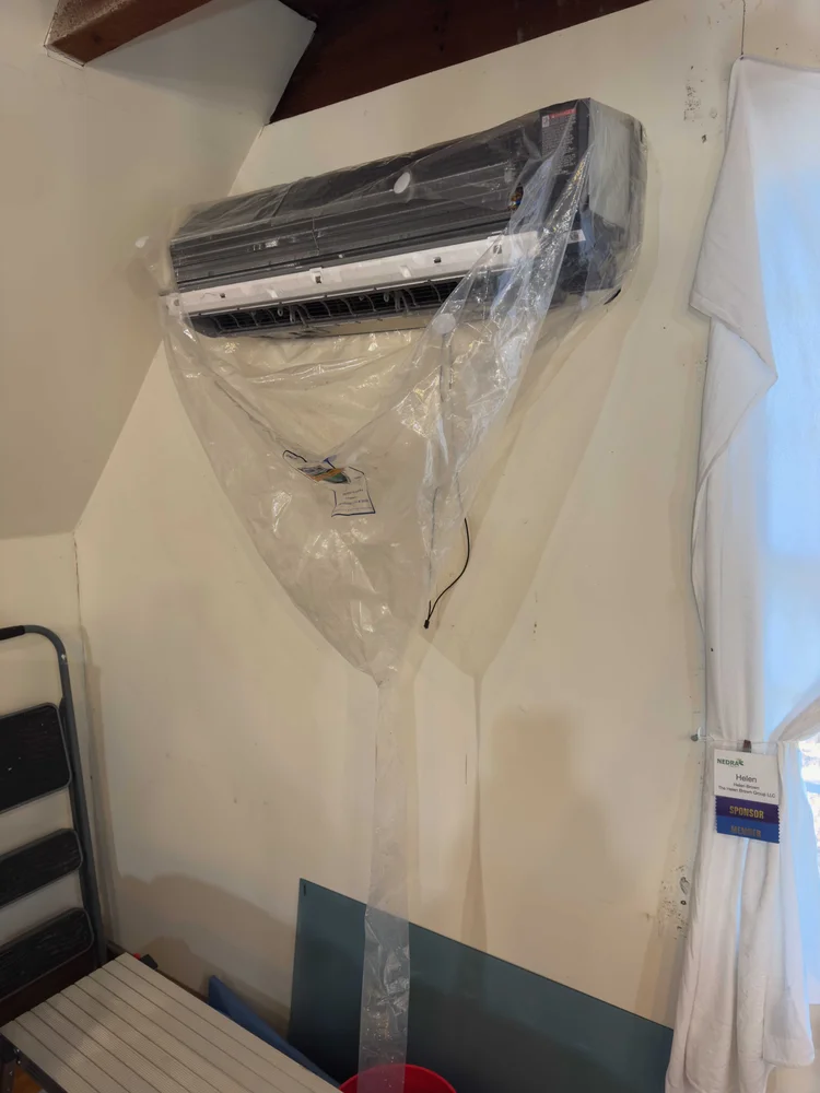 Wall-mounted mini split protected with a cleaning bag during professional service.