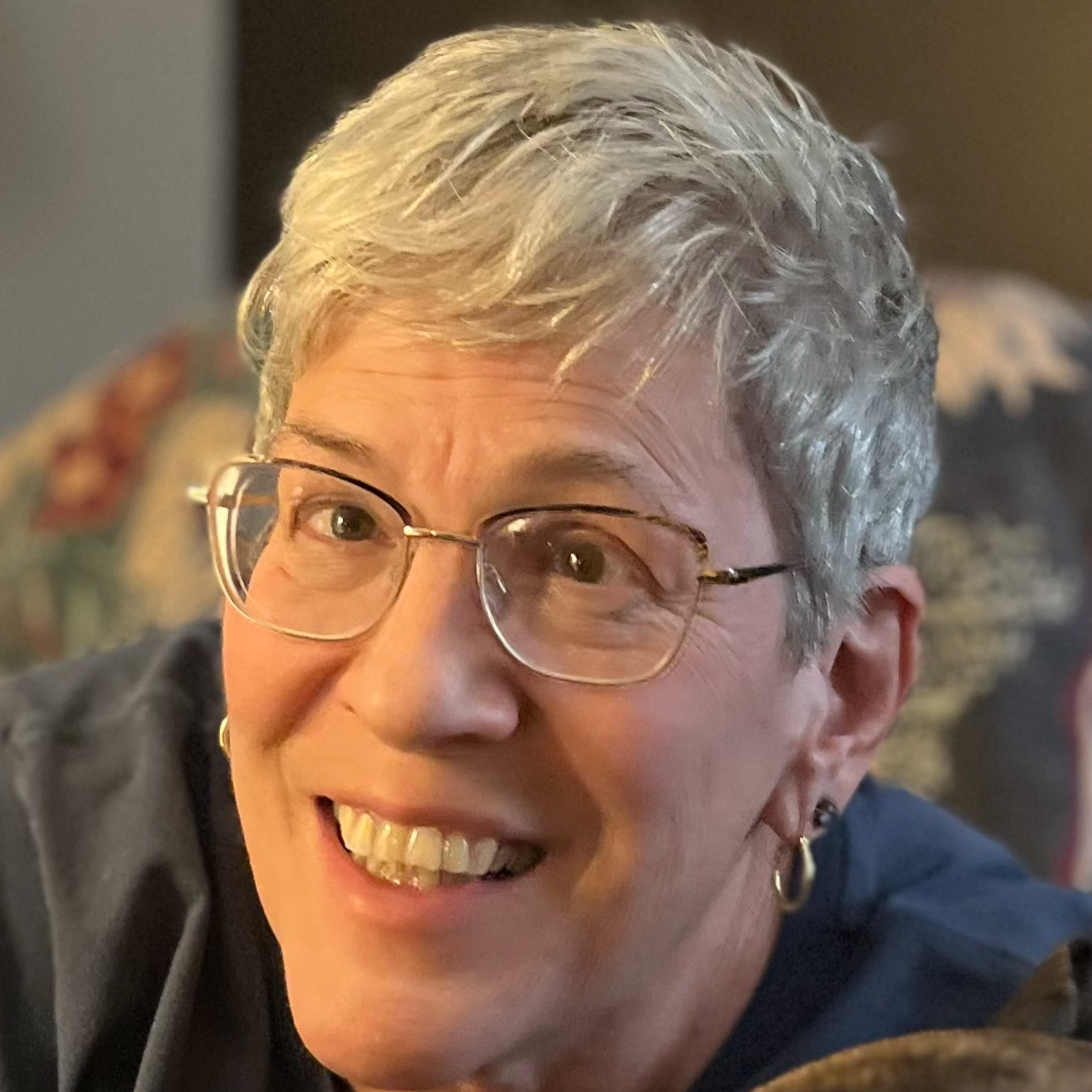 Smiling person with short gray hair and glasses
