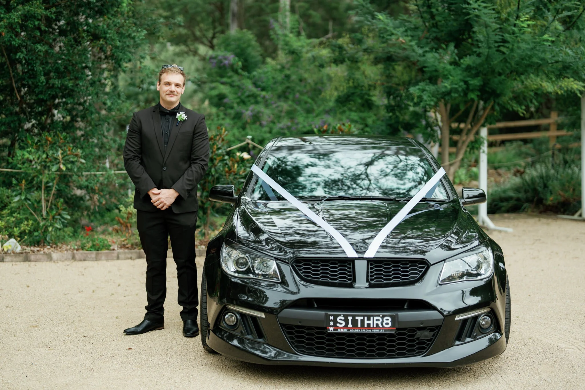 Groom Poses Beside Wedding Car at Kangy Gardens